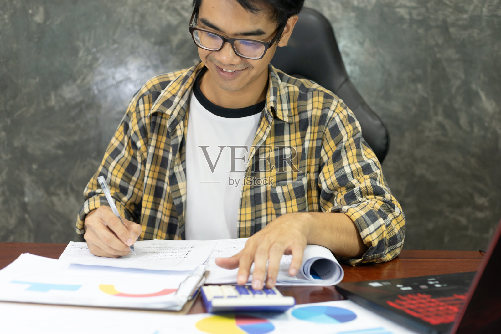 年轻的亚洲企业家在家为金融报纸工作。经营一家初创公司的商人在办公桌旁计算和处理账单发票。照片摄影图片