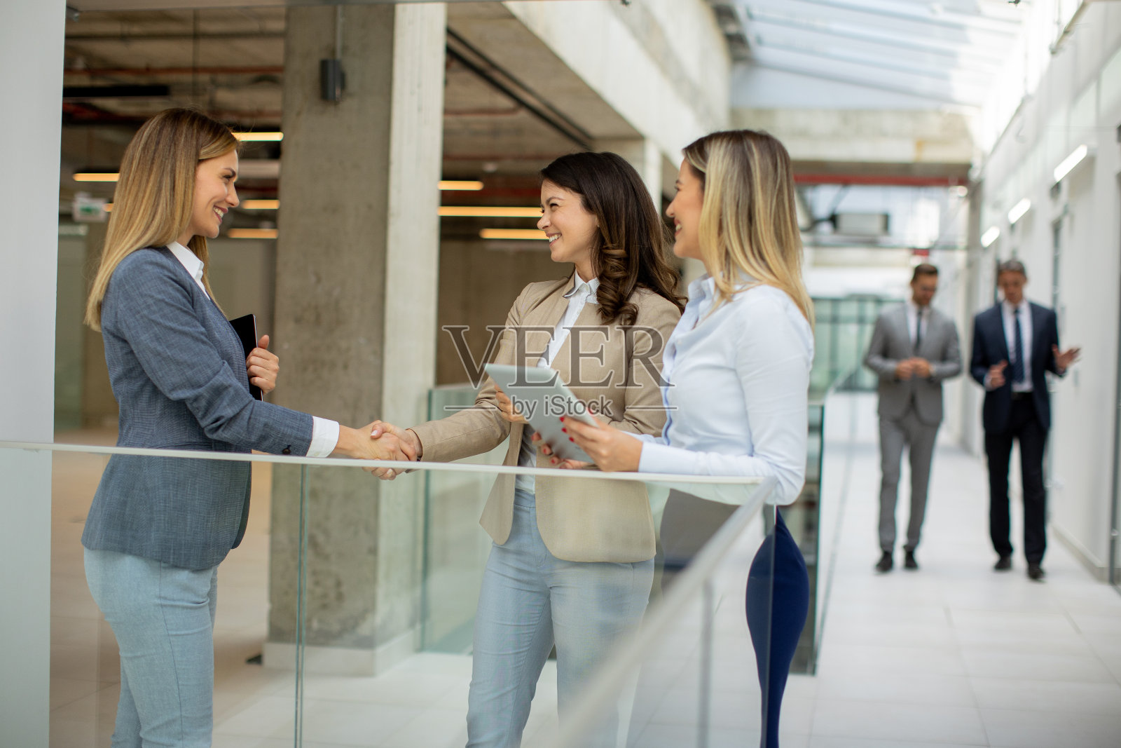 三个年轻的女商人在办公室走廊里讨论照片摄影图片