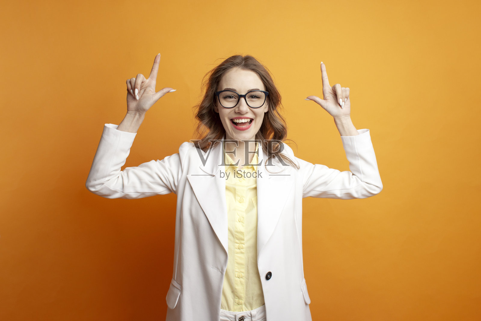 戴着眼镜，穿着白色夹克的漂亮女孩举起双手，一个商务风格的女人在广告复制空间照片摄影图片