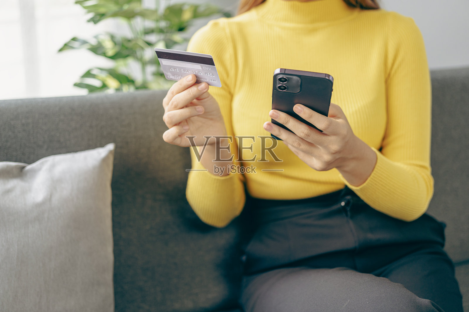 沙发上的信用卡、手机和笔记本电脑、网上购物、电子商务和支付让中国的亚洲男人输入银行信息变得很容易照片摄影图片