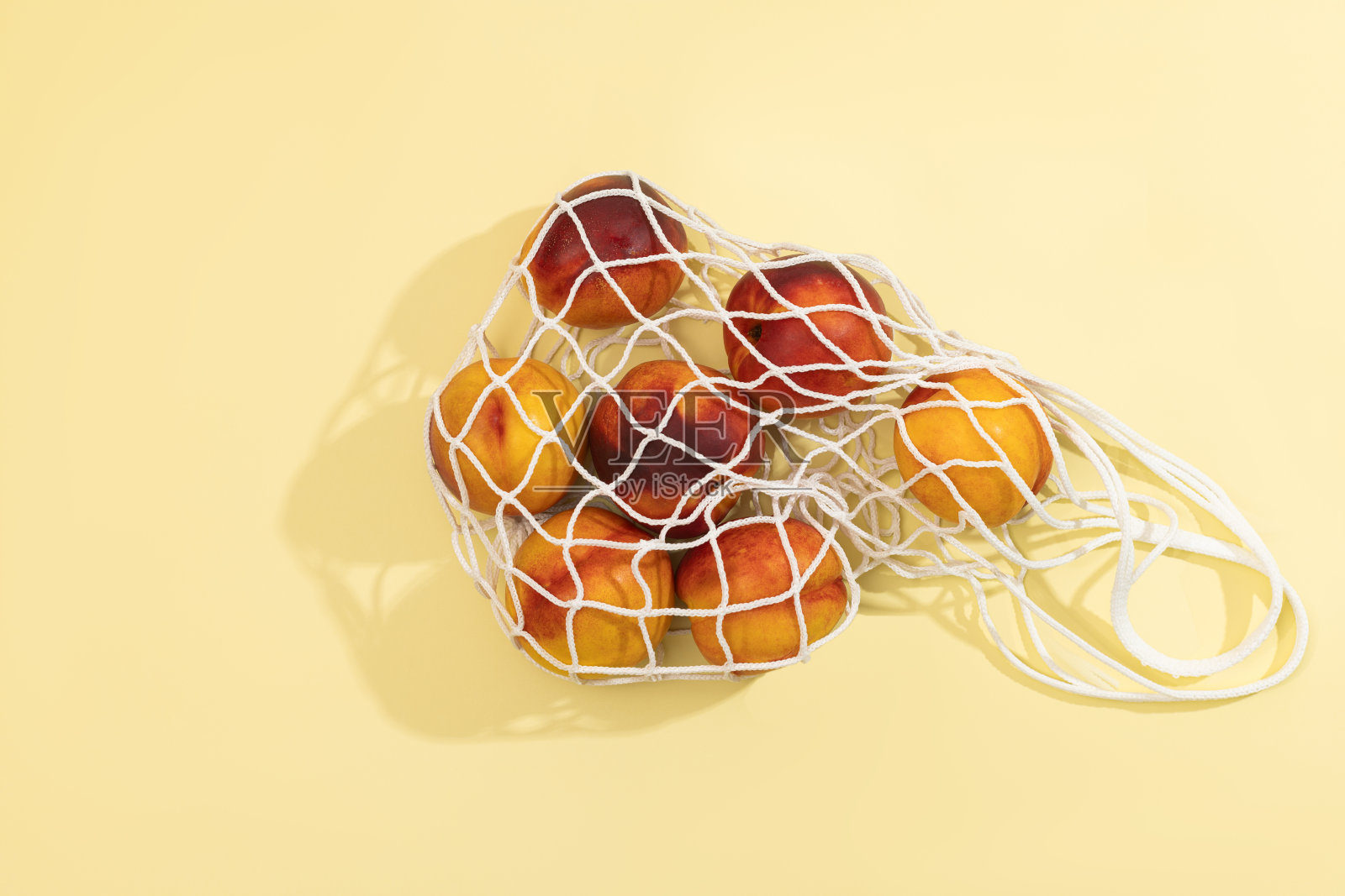 油桃装在白色细绳袋里，背景是彩色的照片摄影图片