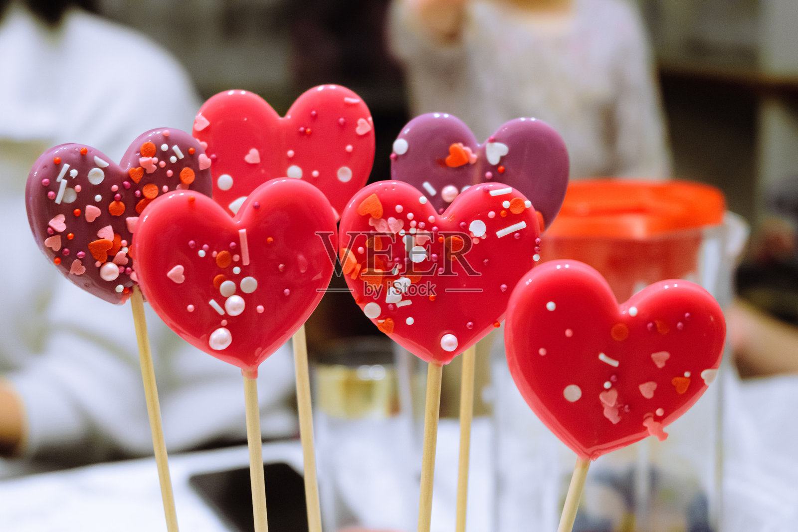 木棒上的心形棒棒糖。不同深浅的红色糖果。景深有限。照片摄影图片