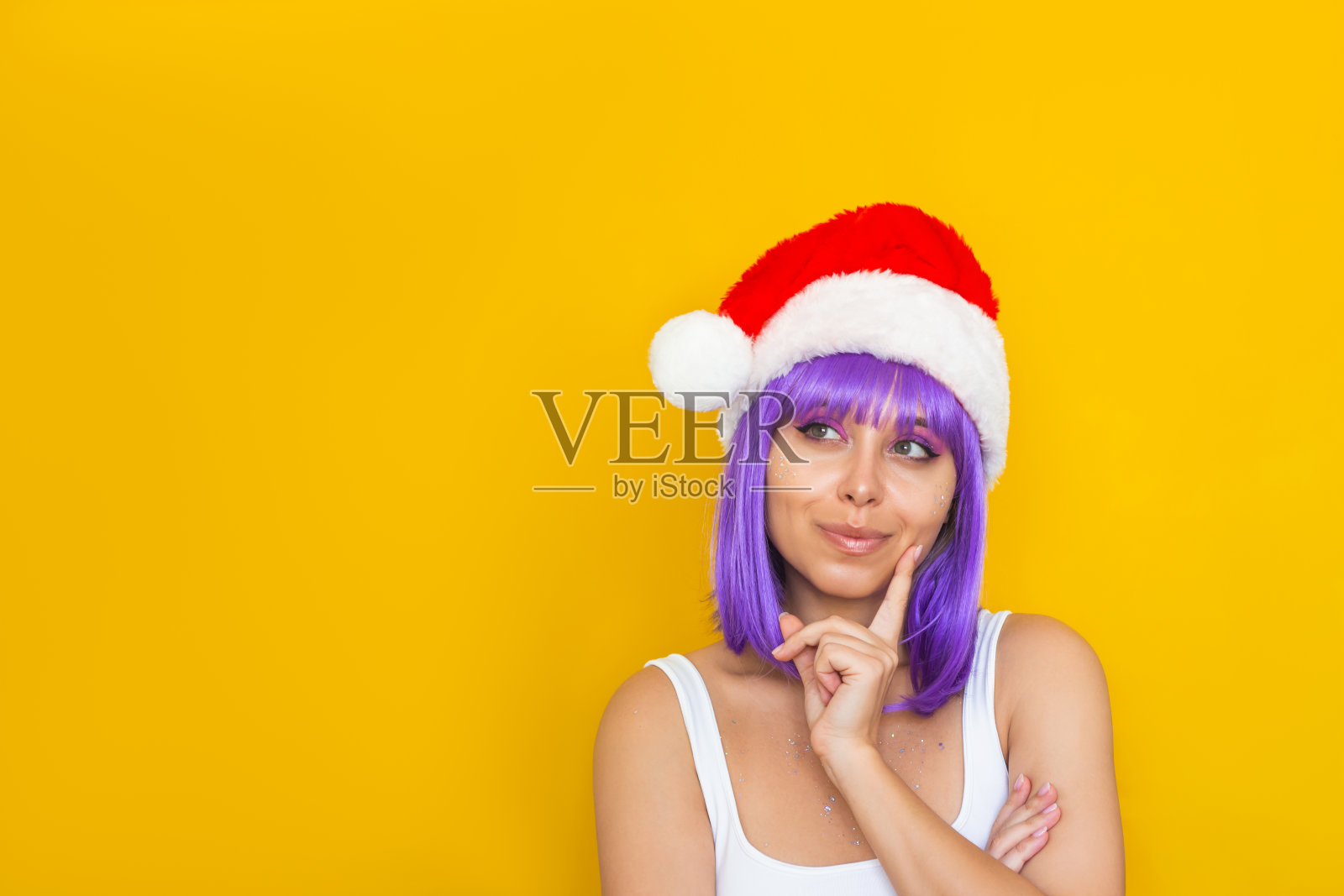 年轻体贴的女人，带着圣诞老人的帽子，紫罗兰色的头发，看着空白的复印空间照片摄影图片