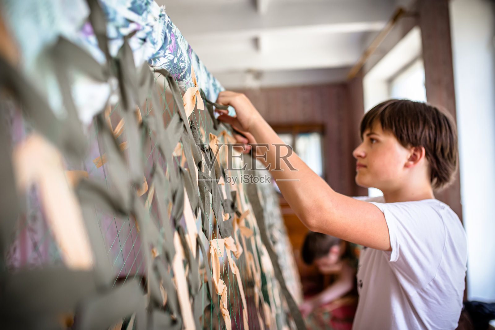 乌克兰足智多谋的年轻人正在为军事用途制作重要的伪装网照片摄影图片
