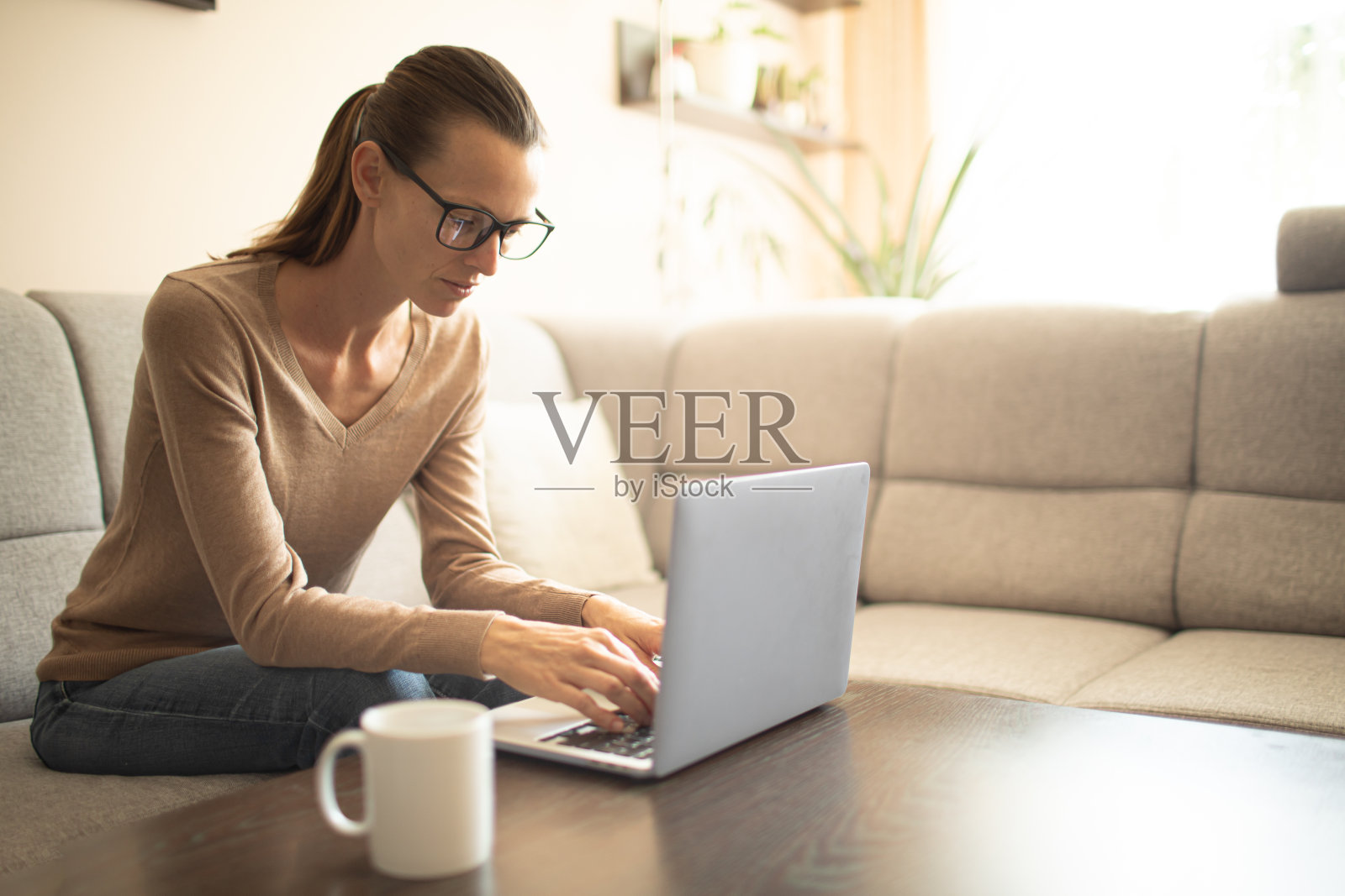 女人在家里使用笔记本电脑。照片摄影图片