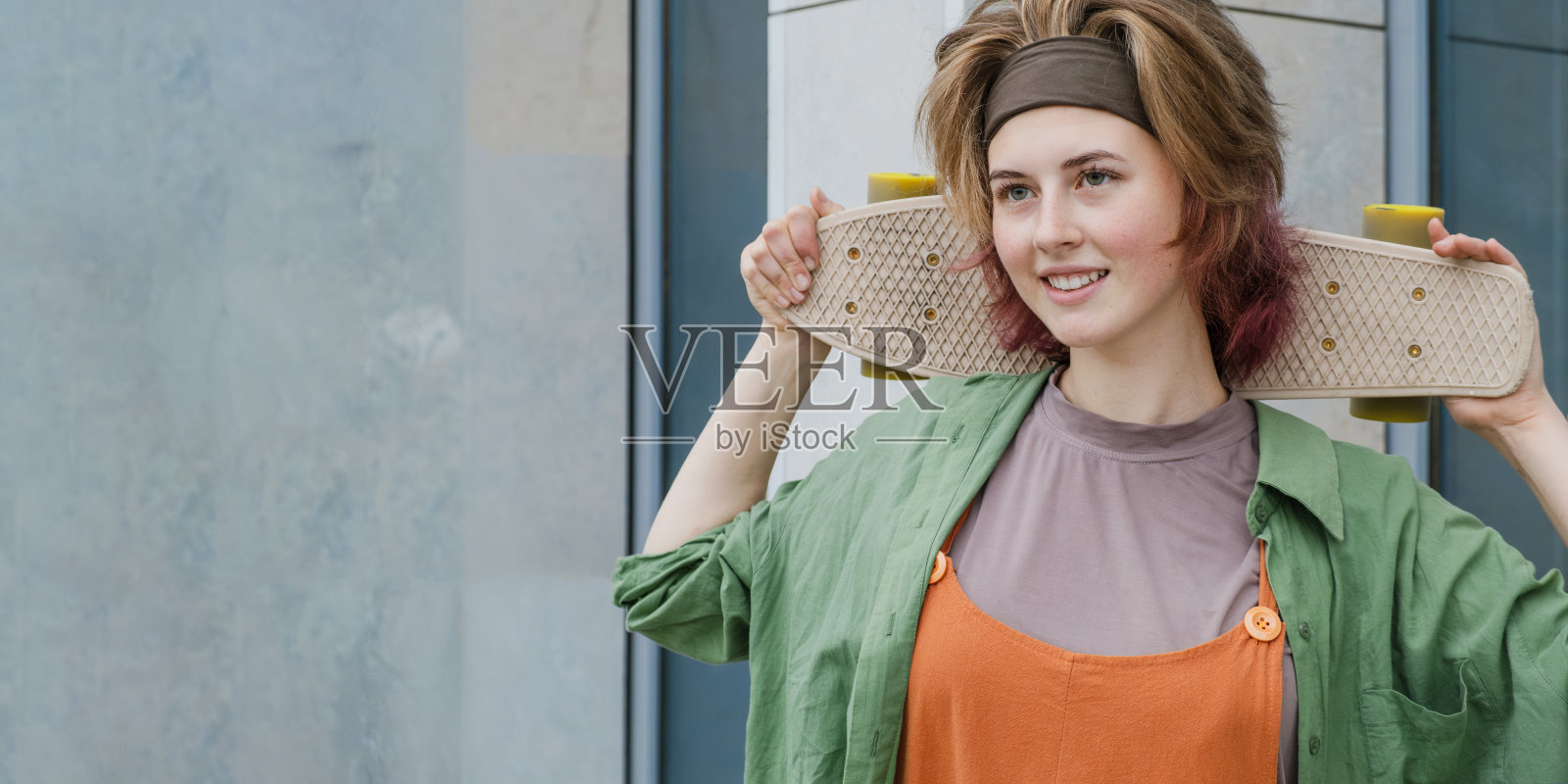 滑冰者手持滑板的年轻女子。滑板运动的概念。横幅，复制空间。照片摄影图片