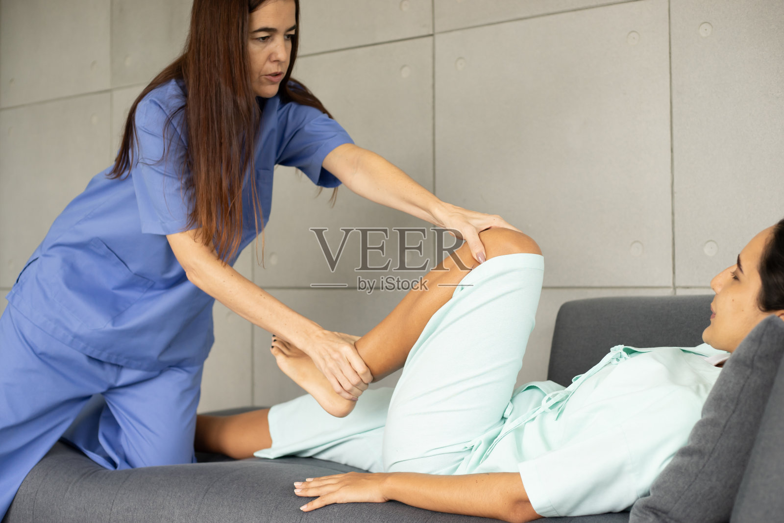 女性白种人物理治疗师与西班牙裔患者的康复。医生在病人疼痛的身体上做伸展运动，进行治疗和康复保健。照片摄影图片