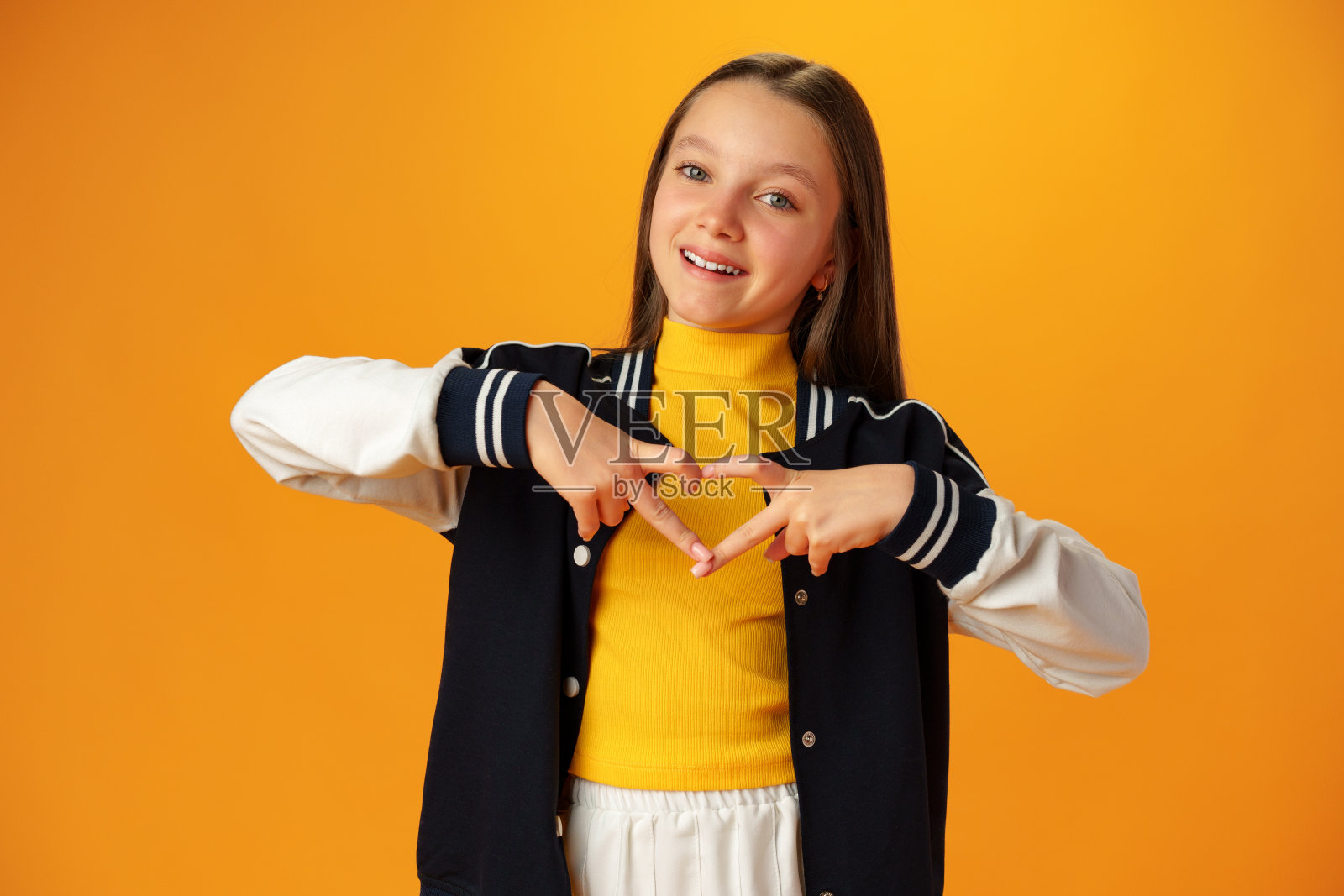 友好的十几岁的女孩在黄色背景上展示了内心的爱照片摄影图片