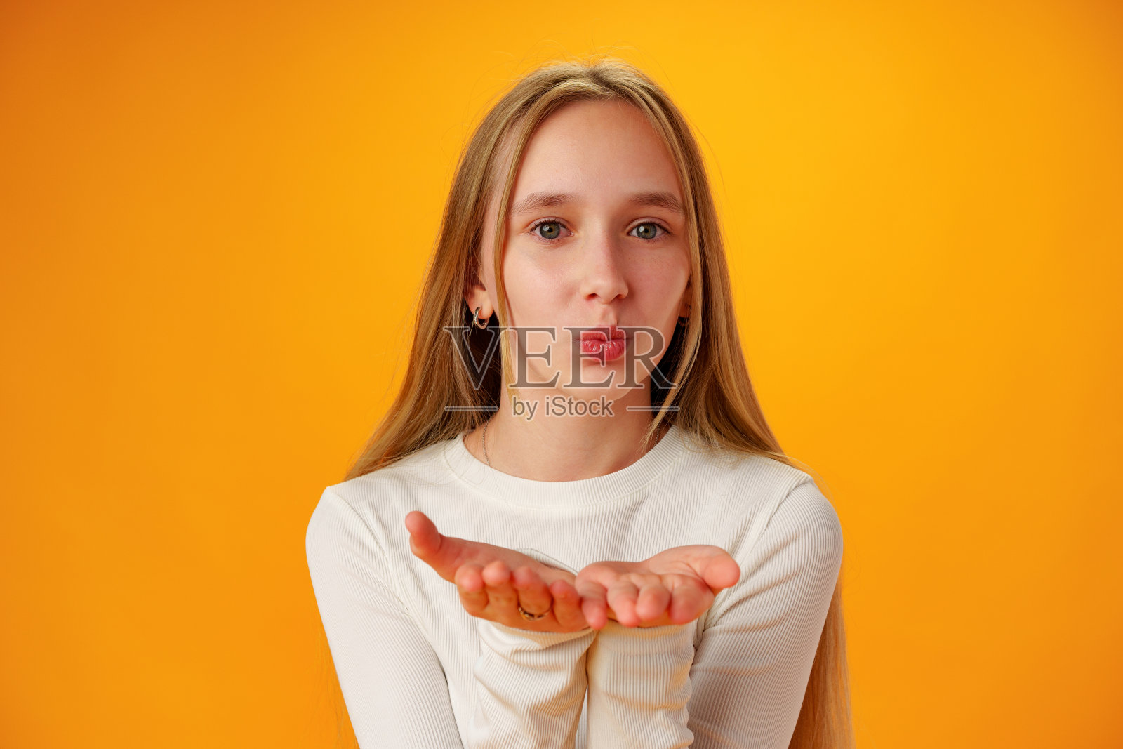 十几岁的女孩在工作室的黄色背景下飞吻照片摄影图片