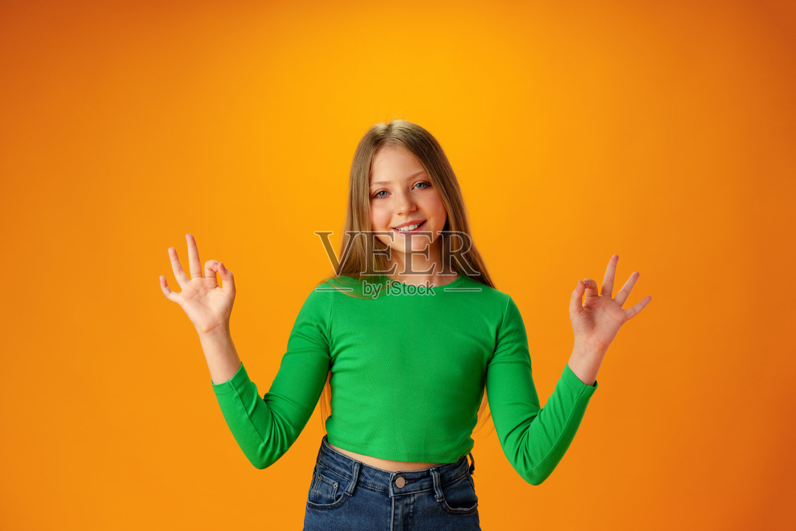 微笑的少女在黄色背景下展示ok的标志照片摄影图片