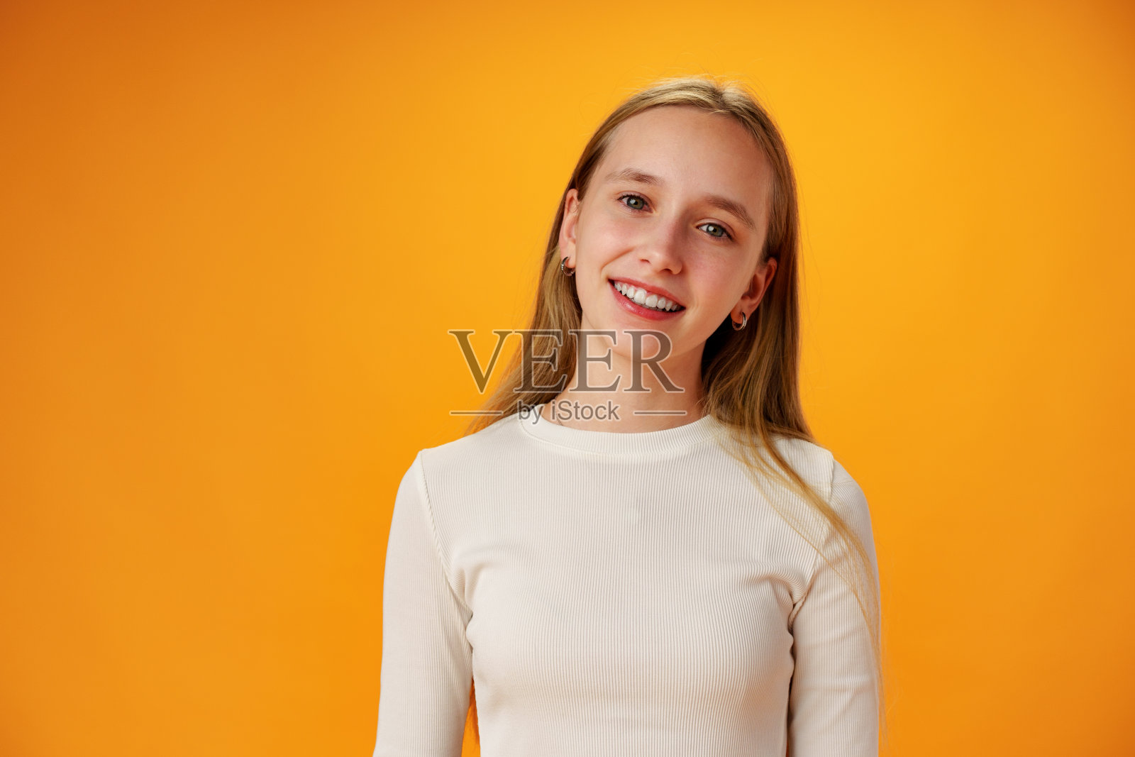 照片中的十几岁的女孩微笑的肖像在工作室的黄色背景照片摄影图片
