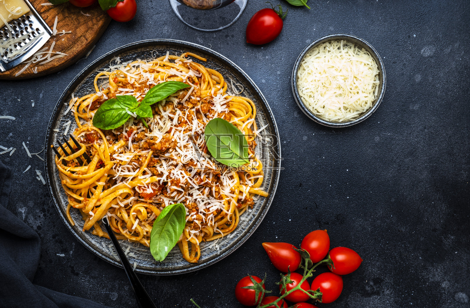 肉酱意大利面或肉末番茄酱意大利面，配绿罗勒和基安蒂红葡萄酒杯，黑色桌面背景，俯视图照片摄影图片