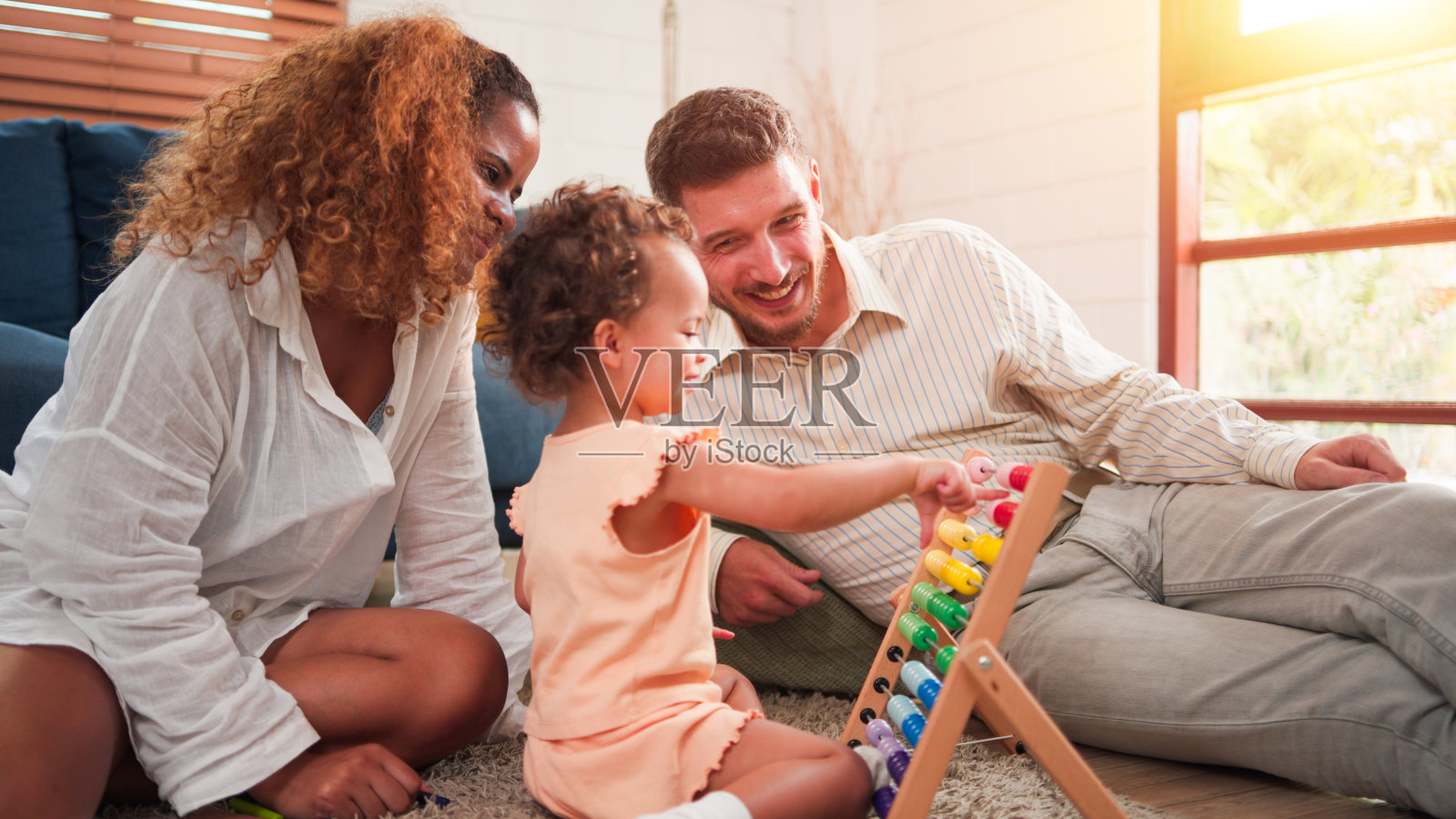 混血儿家庭快乐，年幼的小黑女儿，妈妈和爸爸在家里客厅的地板上一起玩耍。亲子关系的概念。照片摄影图片