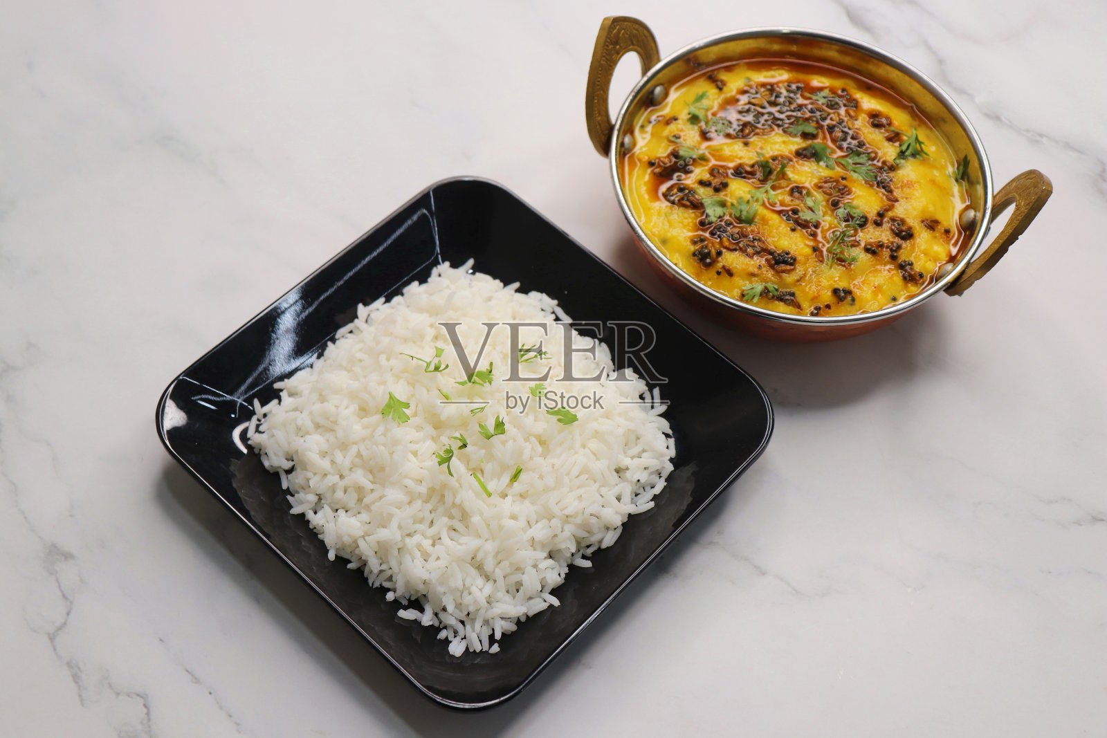 健康营养的印度美食Dal Chawal thali或Dal Rice。在白色背景与复制空间。用酥油、芥菜籽、孜然和香料调成的Dal Tadka。配以香菜。照片摄影图片