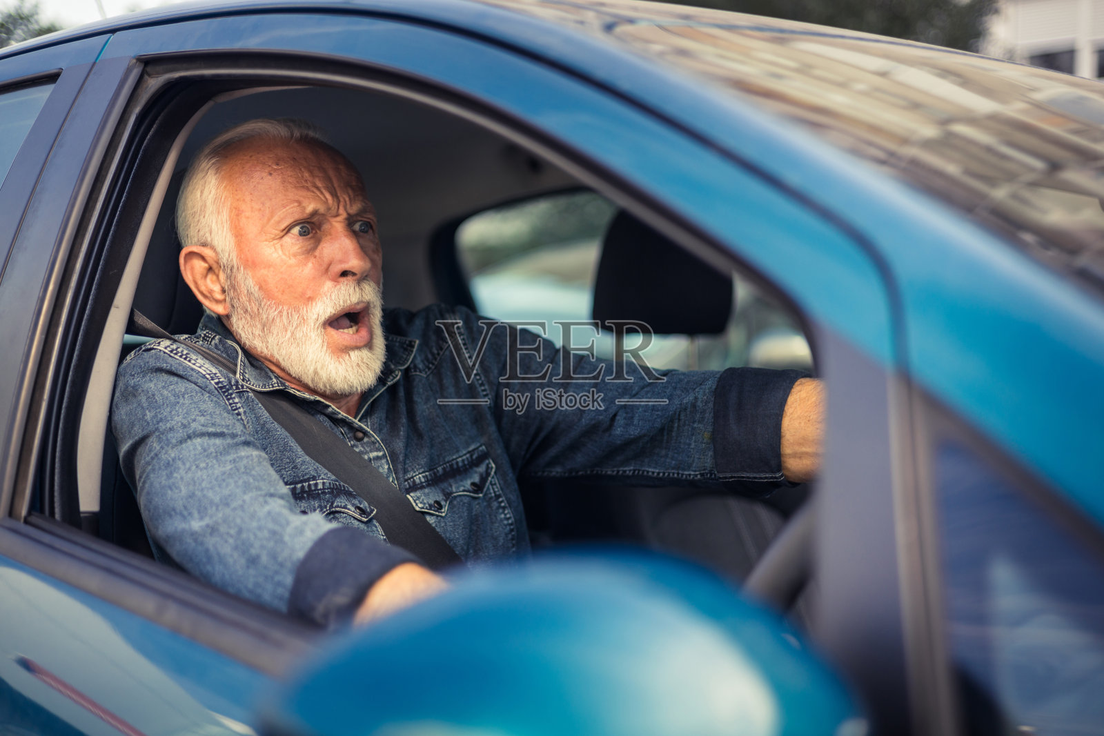 震惊、害怕的男子在事故发生前尖叫并刹车。老人开车快要撞车了。照片摄影图片