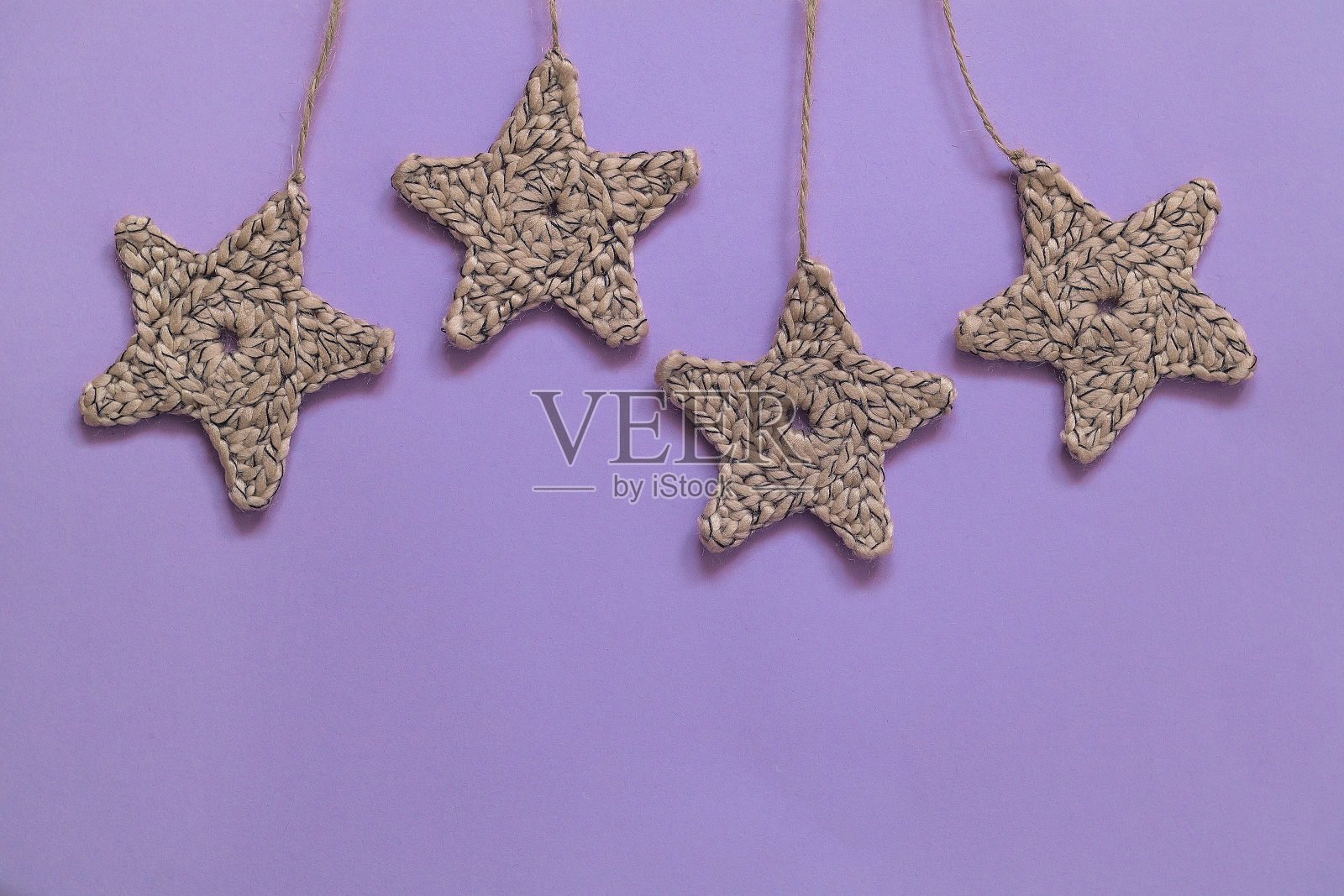 紫色背景上挂着米色星星。副本的空间。照片摄影图片