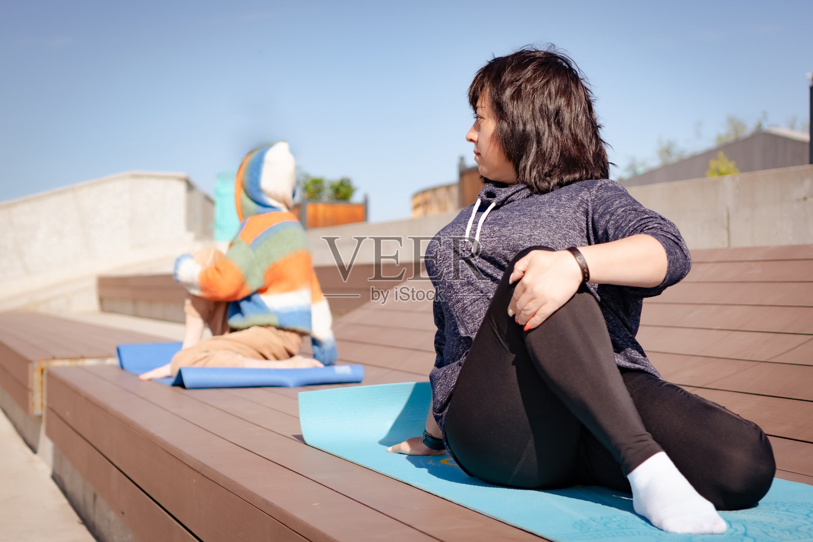 一个成熟的女人在公园的健身垫上揉身体照片摄影图片