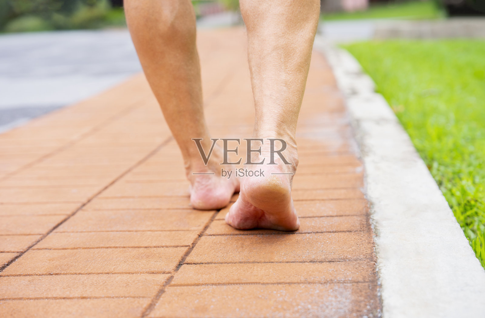 老人赤脚走在公园里的砖人行道上照片摄影图片