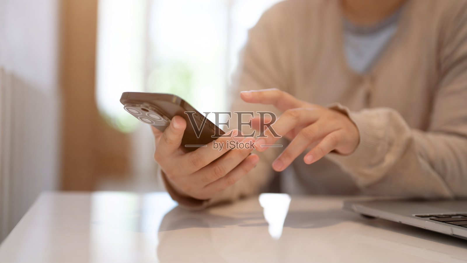一名女子坐在咖啡馆的桌子旁玩智能手机。照片摄影图片