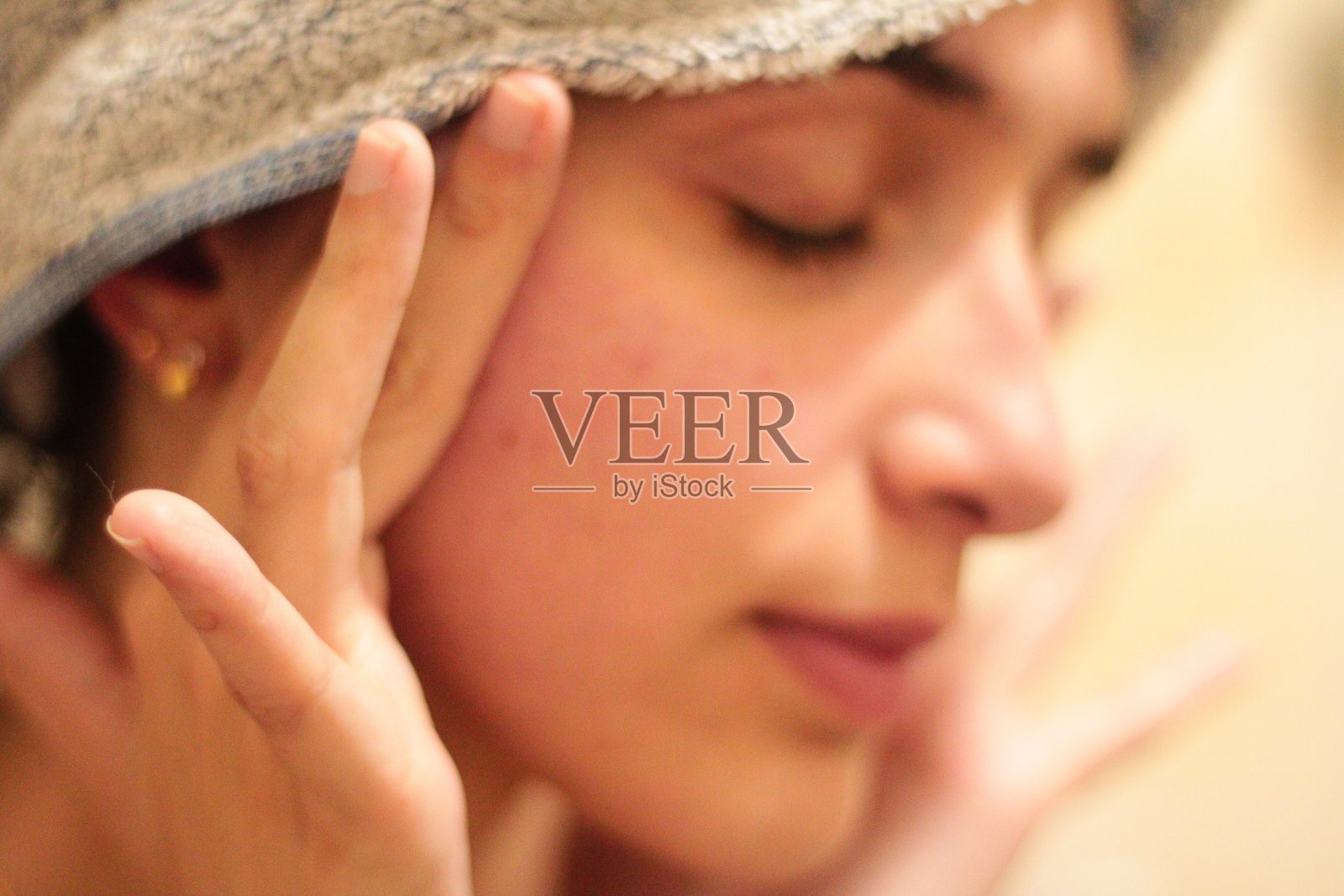 一个年轻女孩在脸上涂面霜的模糊照片照片摄影图片