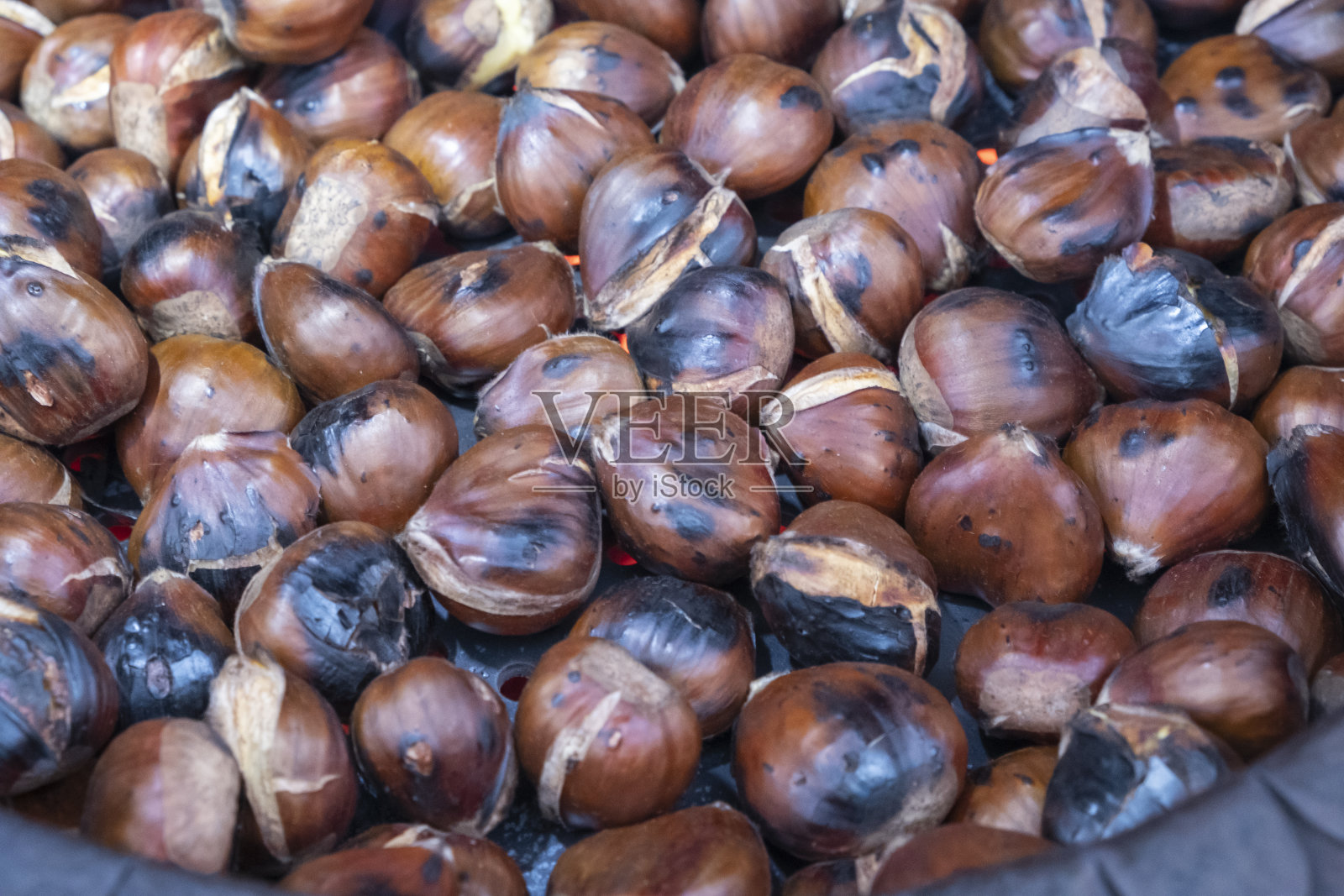 用专门的平底锅在明火上烤栗子照片摄影图片