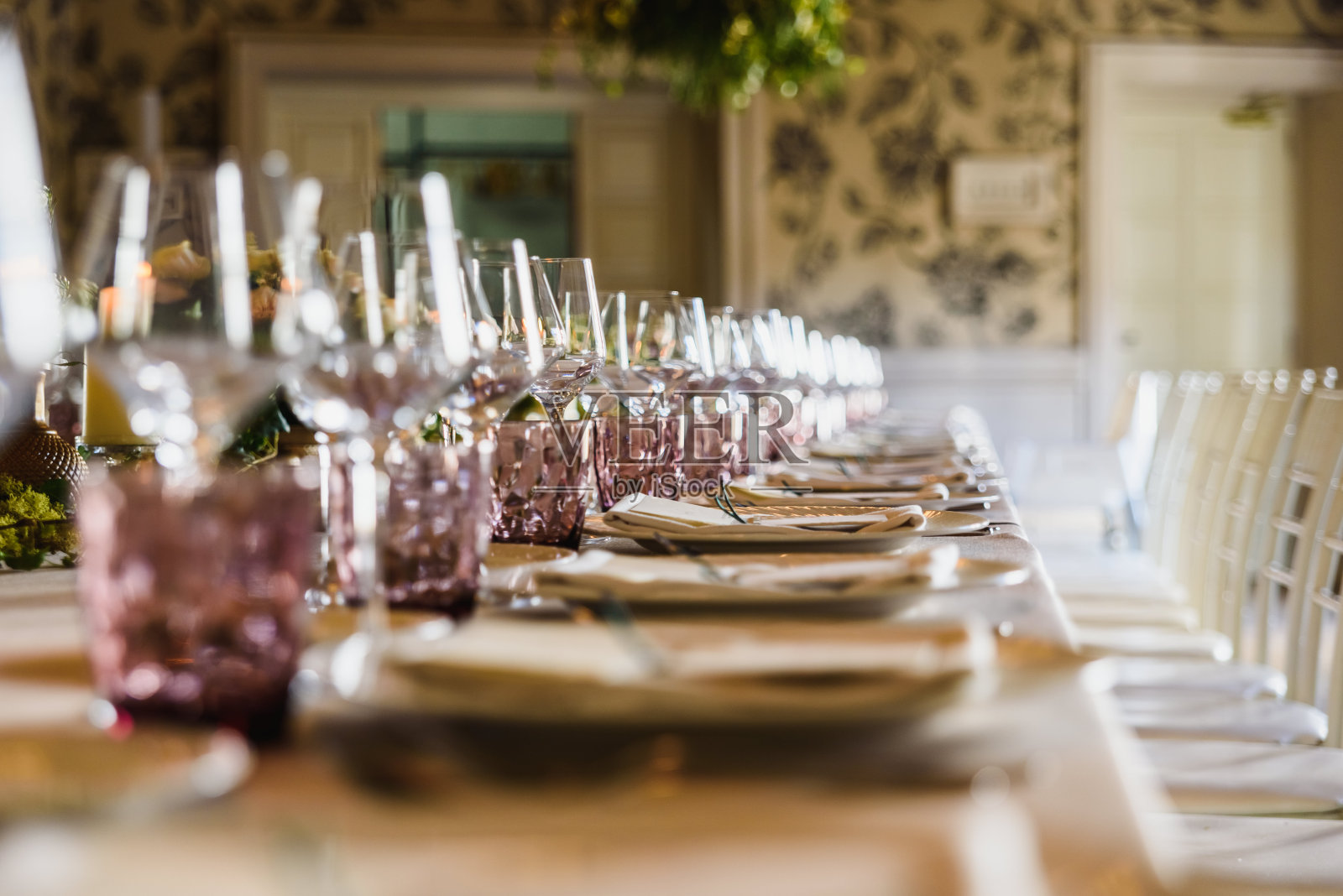 细长的桌子上摆放着优雅的餐具和漂亮的中心装饰品，是装饰婚礼的理想选择。照片摄影图片