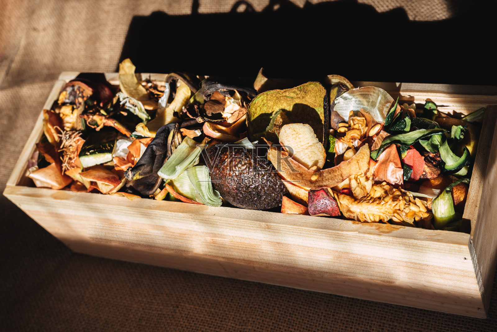 将果皮和有机废物放入木箱中，自制堆肥。照片摄影图片