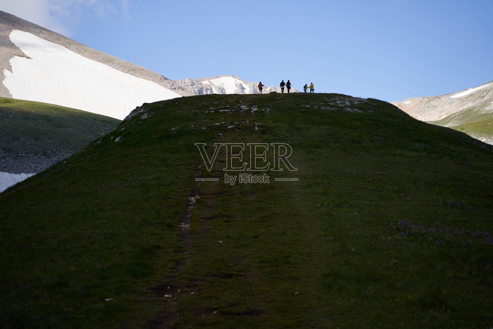一群徒步旅行者住在群山环绕的山顶上。照片摄影图片