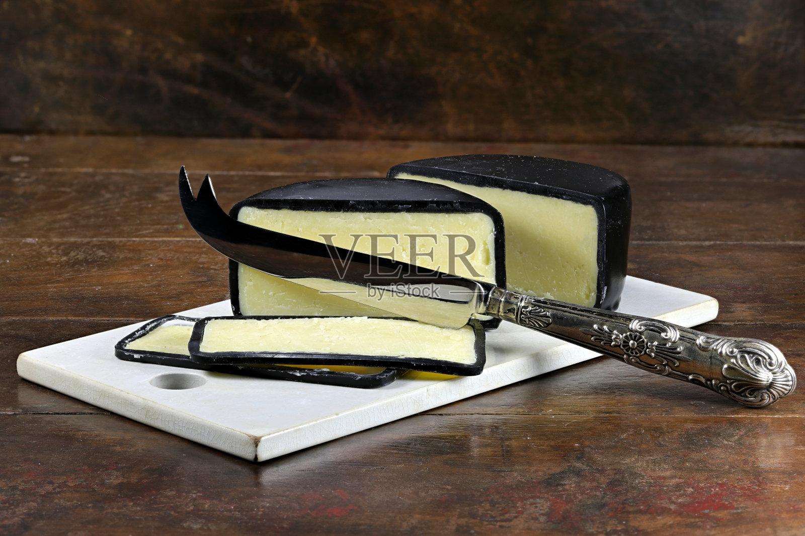 成熟的切达奶酪，用银刀和陶瓷砧板照片摄影图片