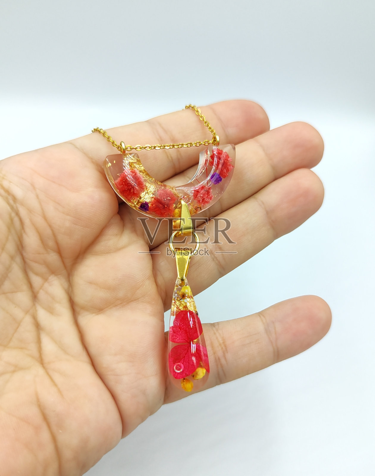 用环氧树脂和天然花朵制作的DIY服装首饰，DIY首饰大师。美丽的耳环和吊坠在家里制作的珠宝树脂。照片摄影图片