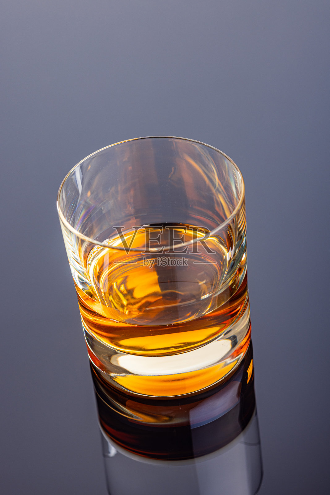 在镜子桌上放一杯威士忌或其他酒精。照片摄影图片