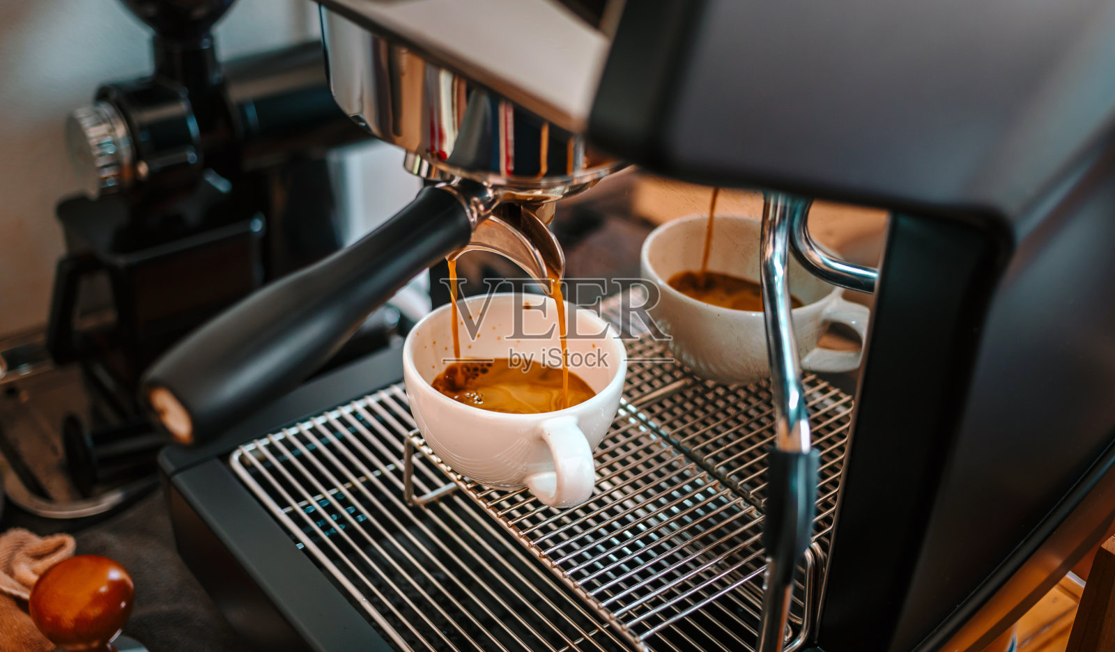 从咖啡机中提取咖啡，用过滤器将咖啡倒入杯中，在咖啡店从咖啡机中倒入浓缩咖啡照片摄影图片