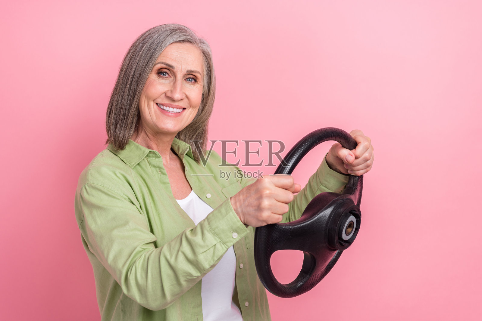 照片可爱的漂亮的积极的高级妇女穿着时尚的衣服骑车辆课驾驶学校孤立的粉红色背景照片摄影图片