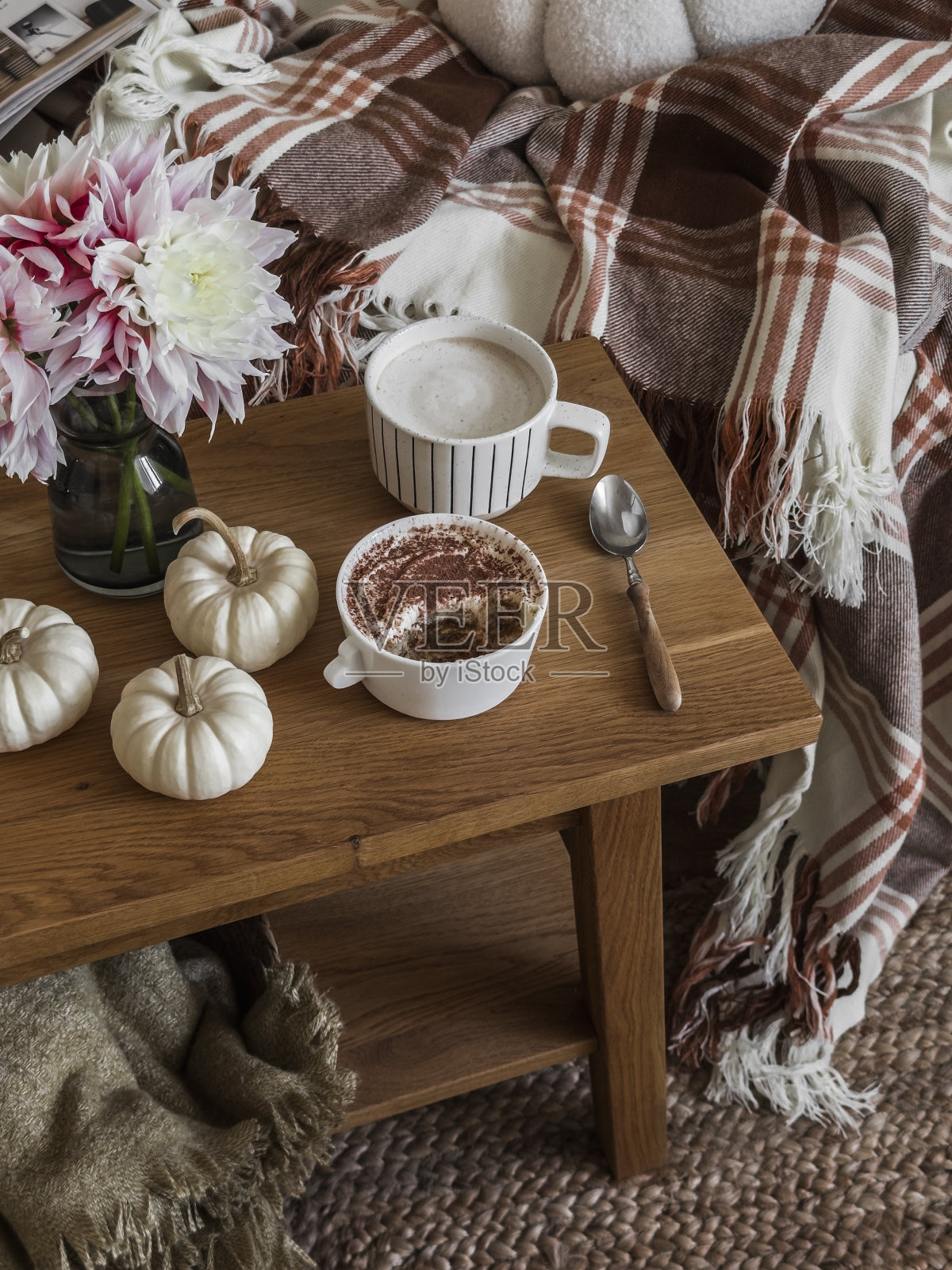 咖啡休息时间——在舒适的客厅里，沙发旁边的木凳上，卡布奇诺，提拉米苏，秋天的装饰照片摄影图片