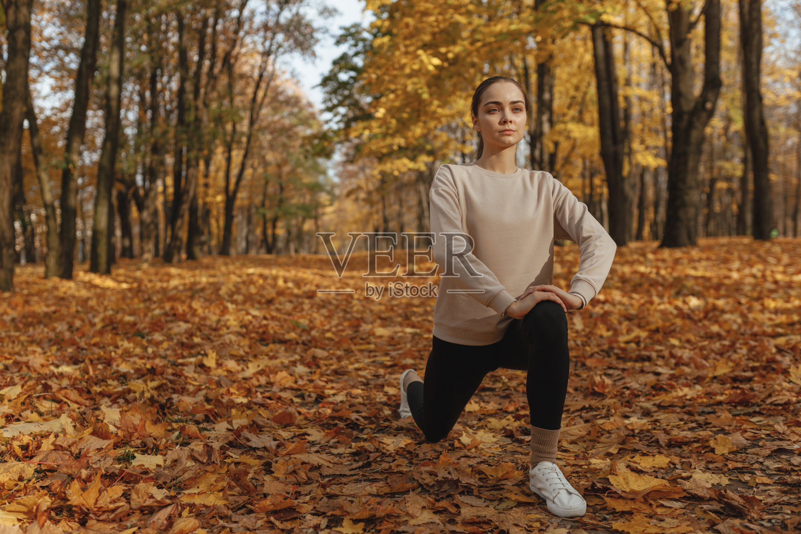 自信的运动女性在秋天的公园里锻炼照片摄影图片