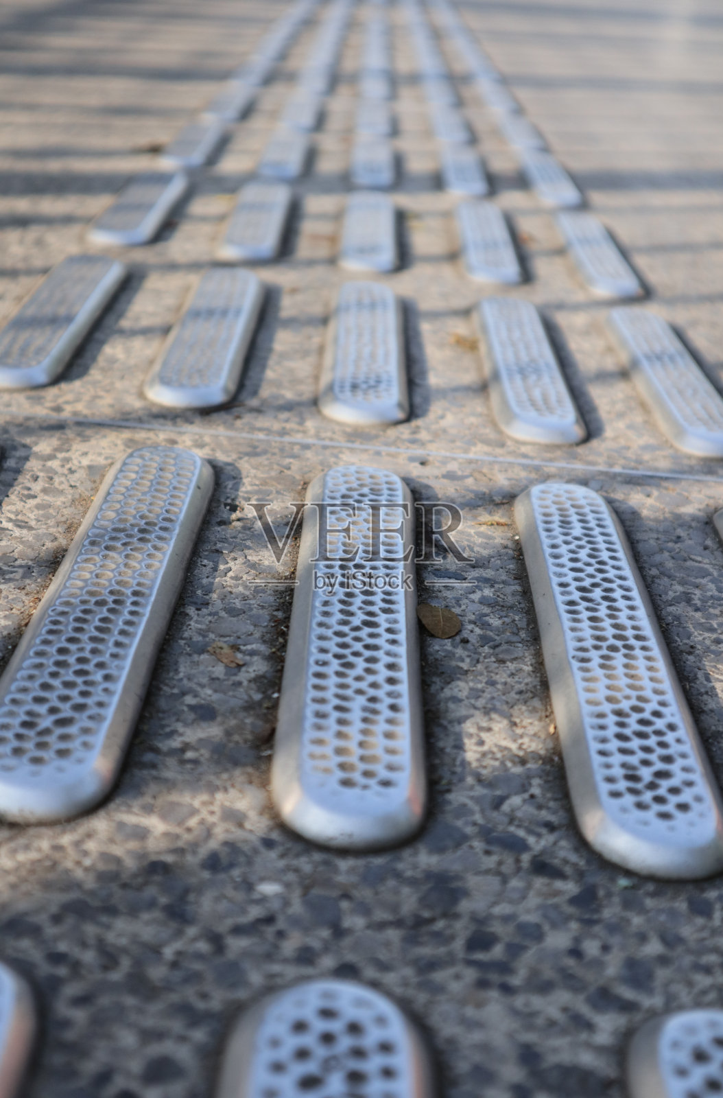 不锈钢触觉铺路与纹理的地面表面的小街。残障盲人专用步行道上的金属装饰品照片摄影图片