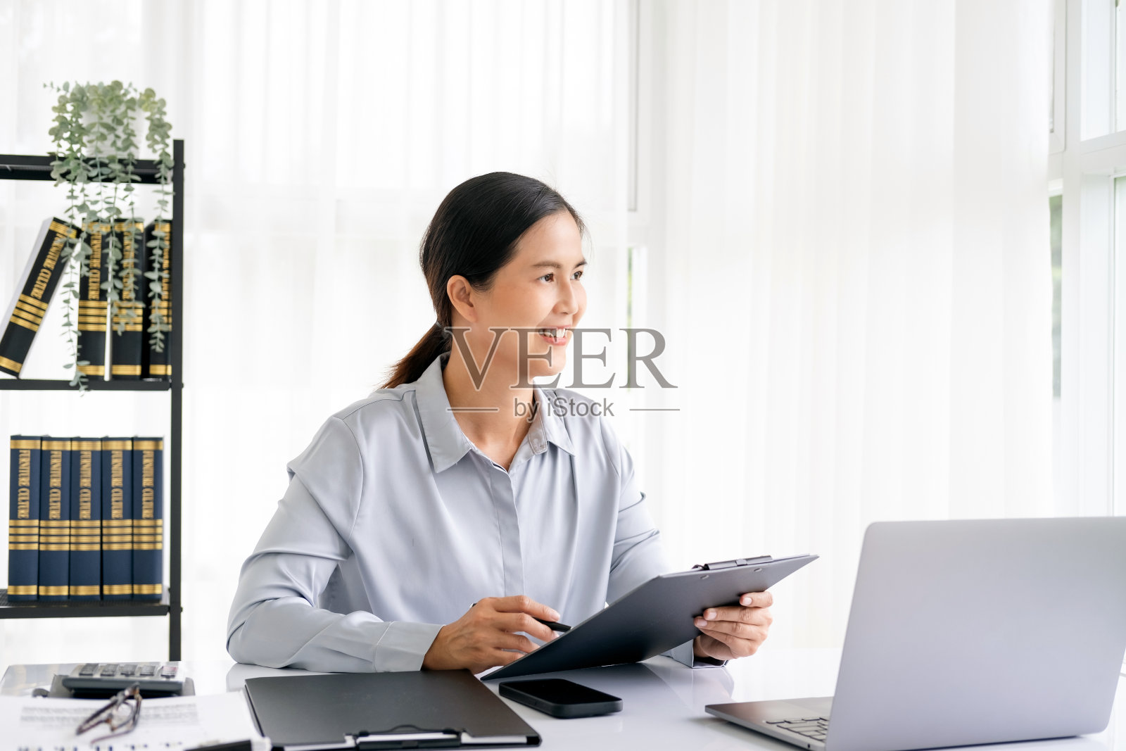 成功、微笑、成熟的女商人在办公室处理文书工作时使用笔记本电脑。照片摄影图片