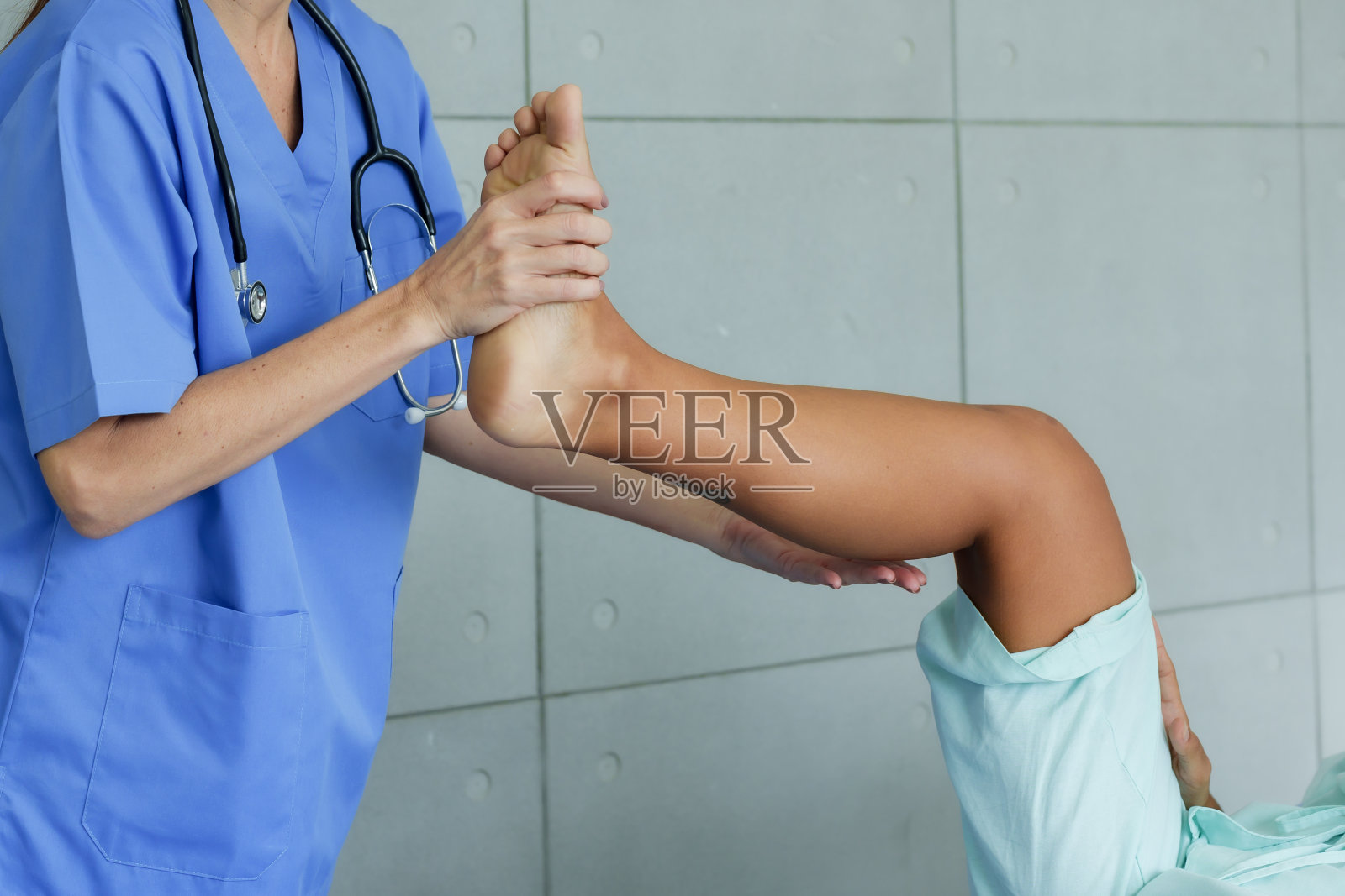 骨科专家介绍女性物理治疗师匿名检查一个生病的西班牙妇女躺在床上的腿和膝关节。通过在医院里前后抬起弯曲的腿照片摄影图片