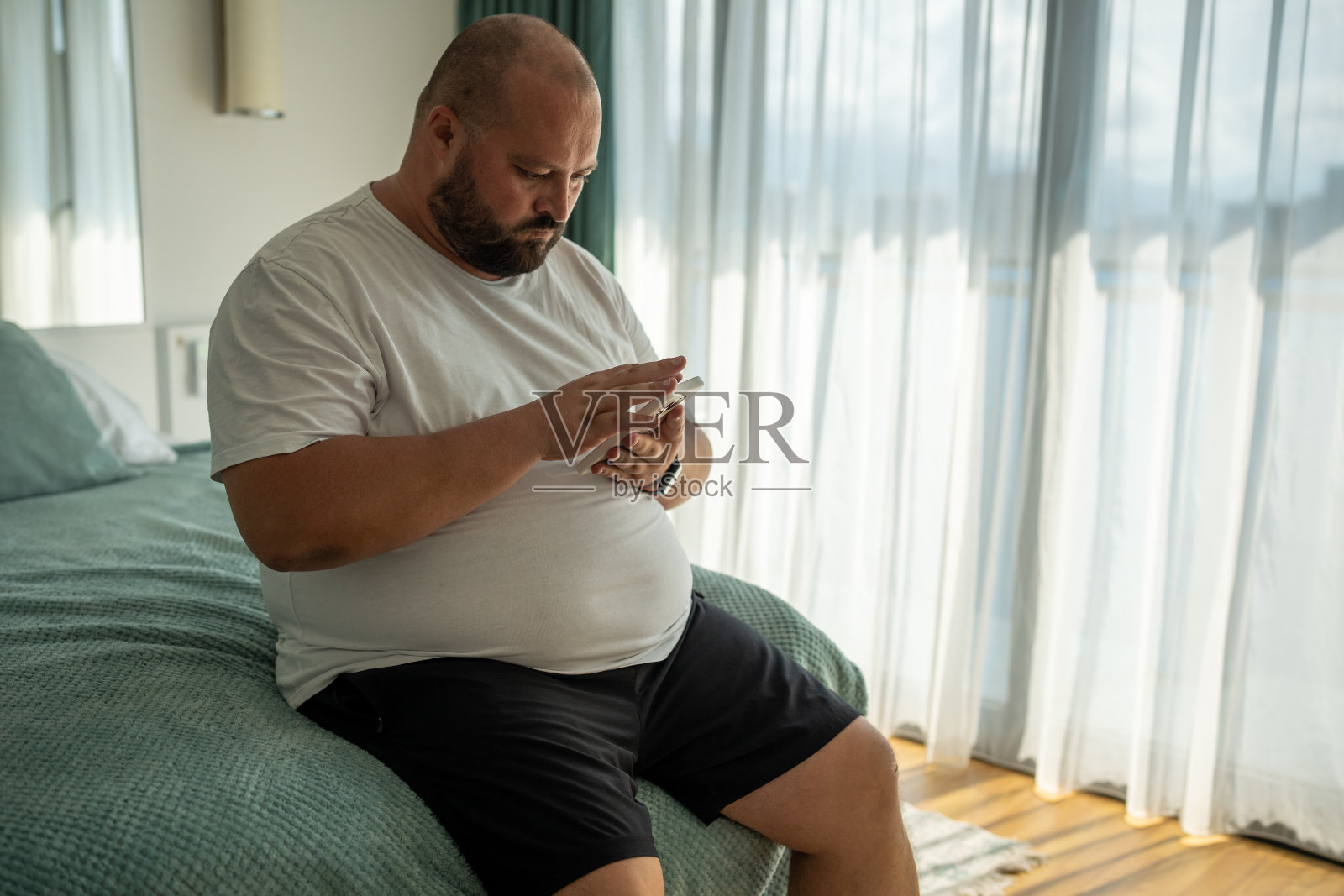 胖胖的秃头大胡子，用智能手机聊天，打电话，发信息，看新闻，看天气照片摄影图片