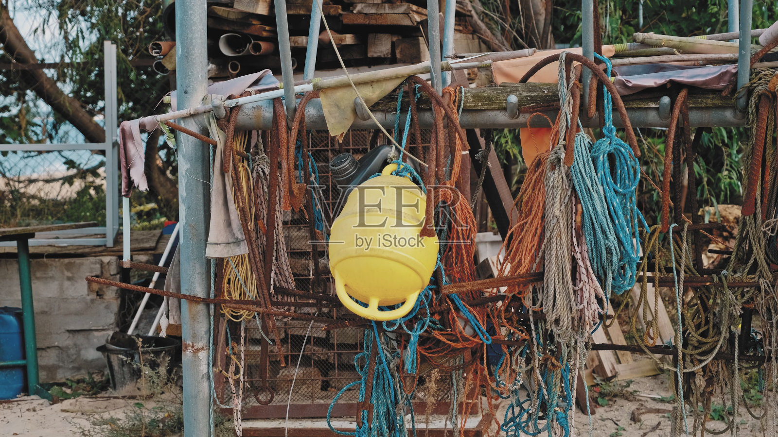 锈迹斑斑的金属钩、浮标、网、绳、海渔具悬挂在海滨滩港照片摄影图片