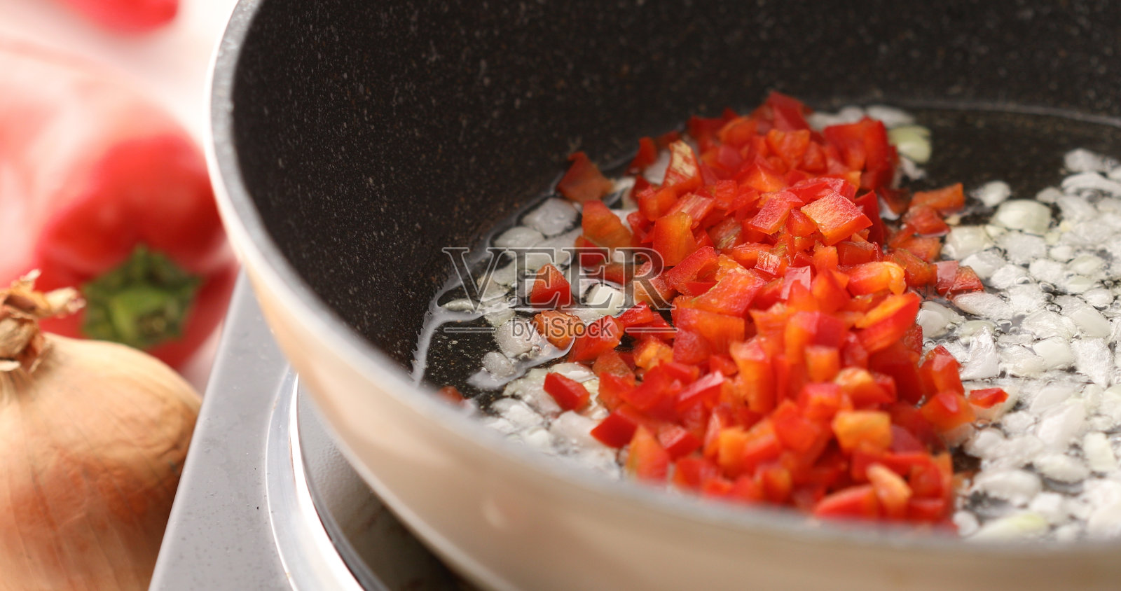 在煎好的洋葱中加入辣椒粉或甜椒。照片摄影图片