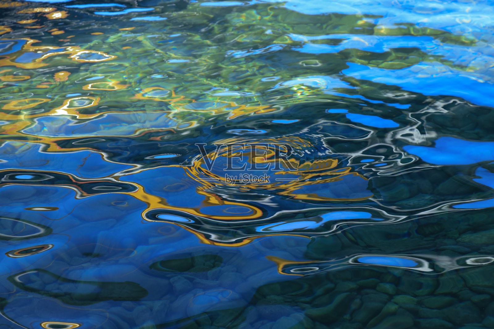 蓝蓝的水面上有黄绿色的涟漪。照片摄影图片