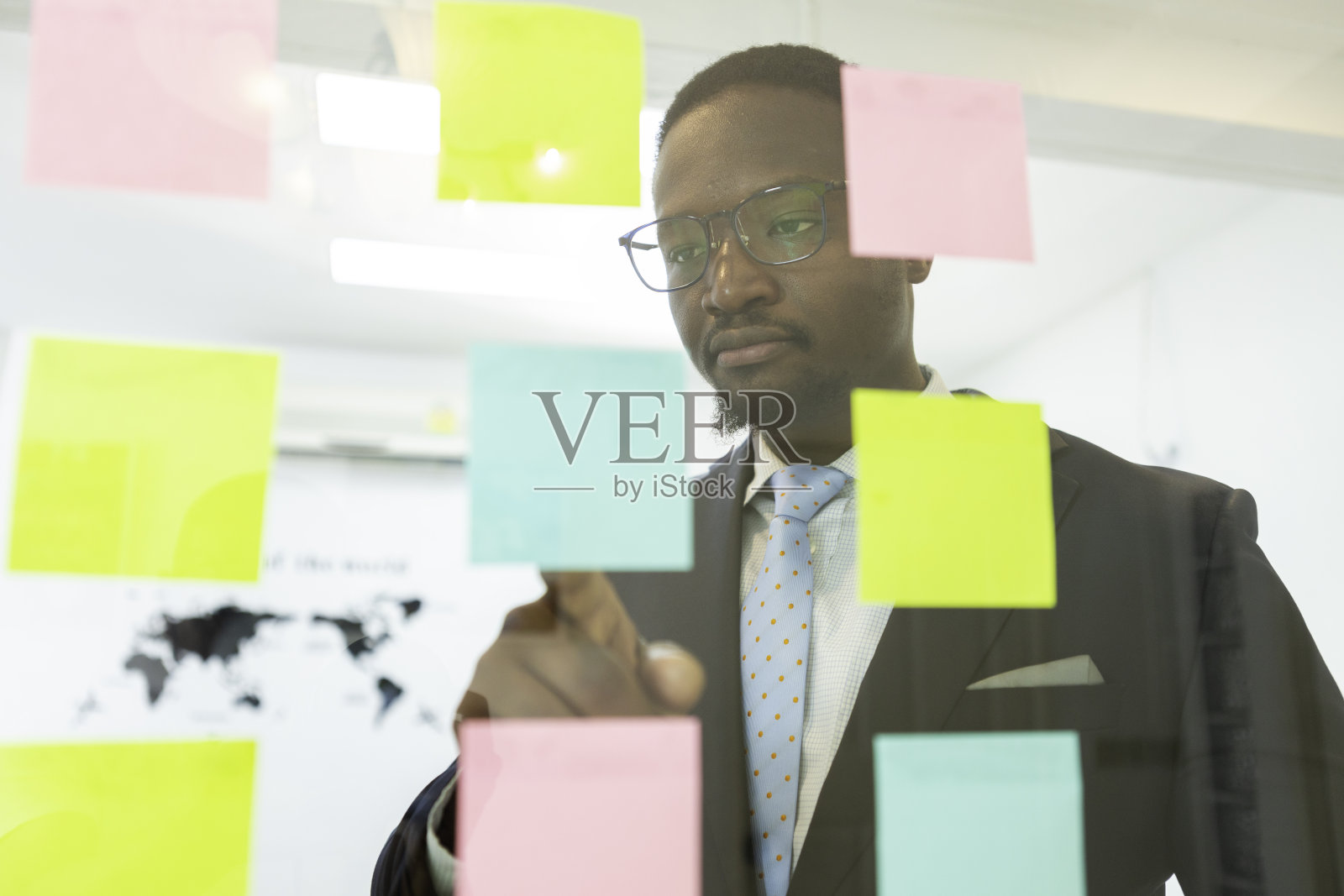 商人非洲会指着玻璃板上张贴它的便条。业务团队在办公室开会，进行头脑风暴，分享想法。策划公司营销策略项目。照片摄影图片