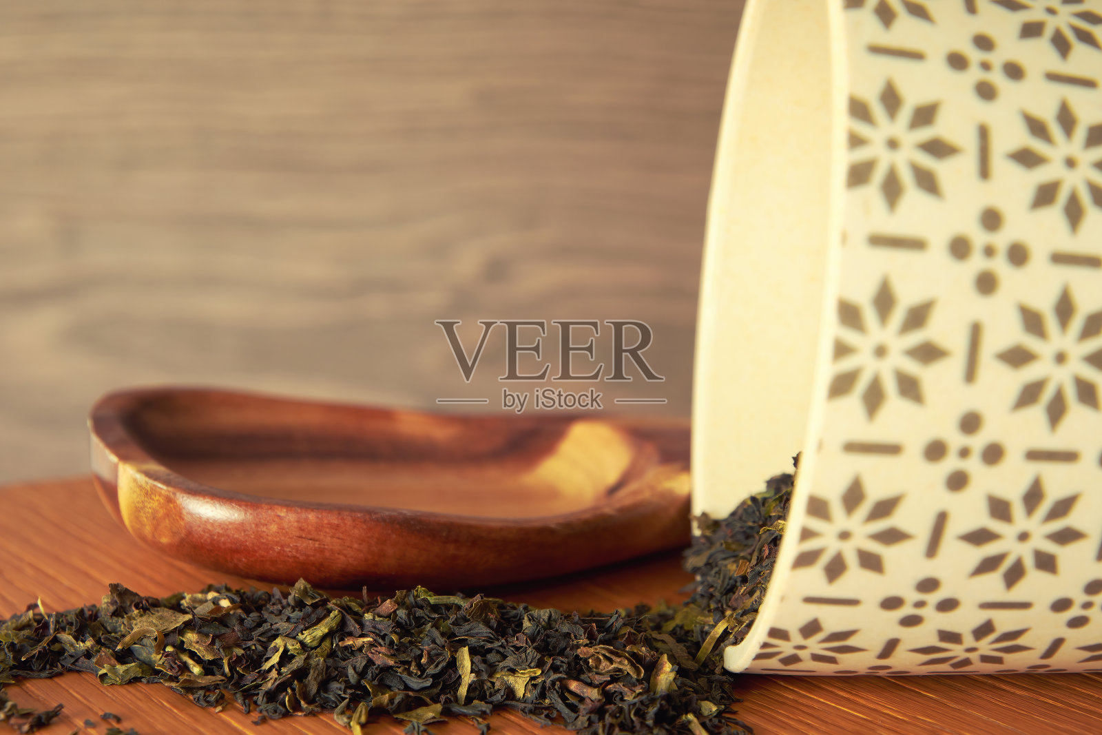 木勺和茶杯的特写镜头，上面有黑色和绿色的干茶叶照片摄影图片