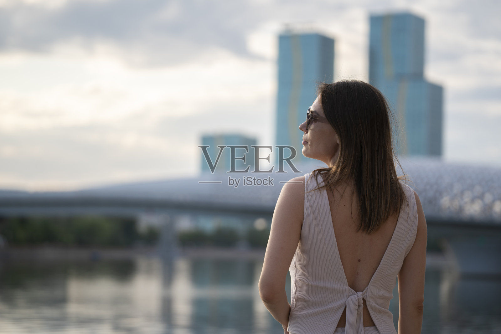 一个戴着墨镜的黑发女子的夏日都市肖像。照片摄影图片