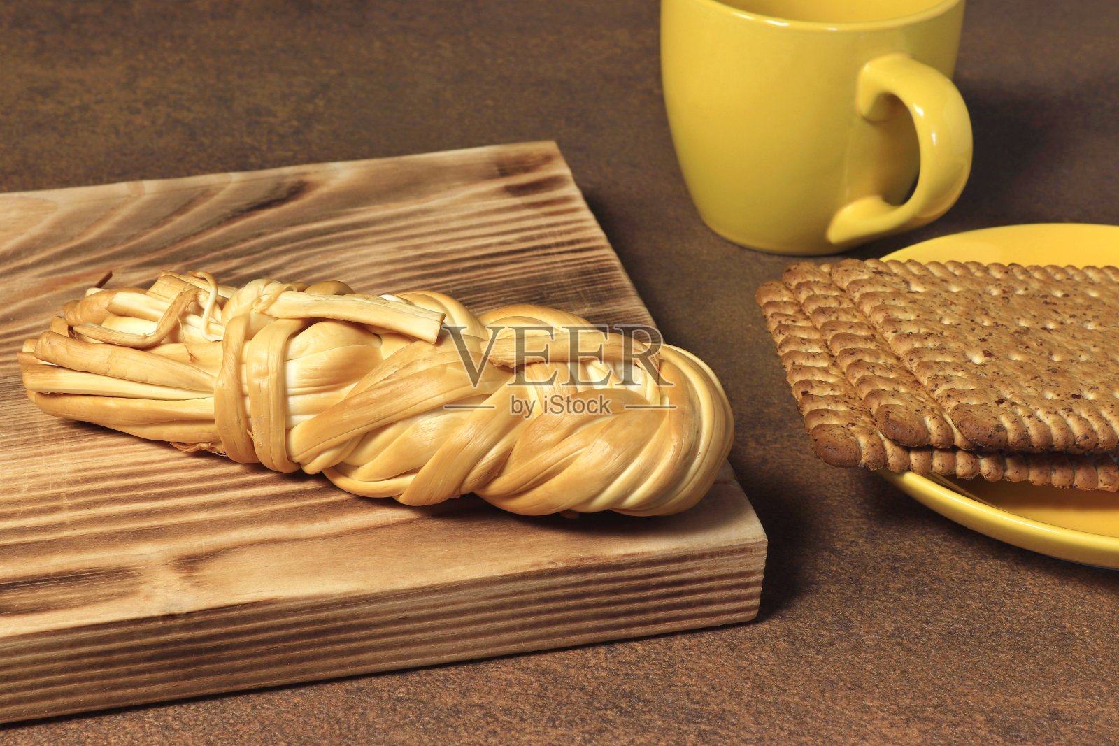 案板上放着编织奶酪，碟子和杯子里放着饼干。照片摄影图片
