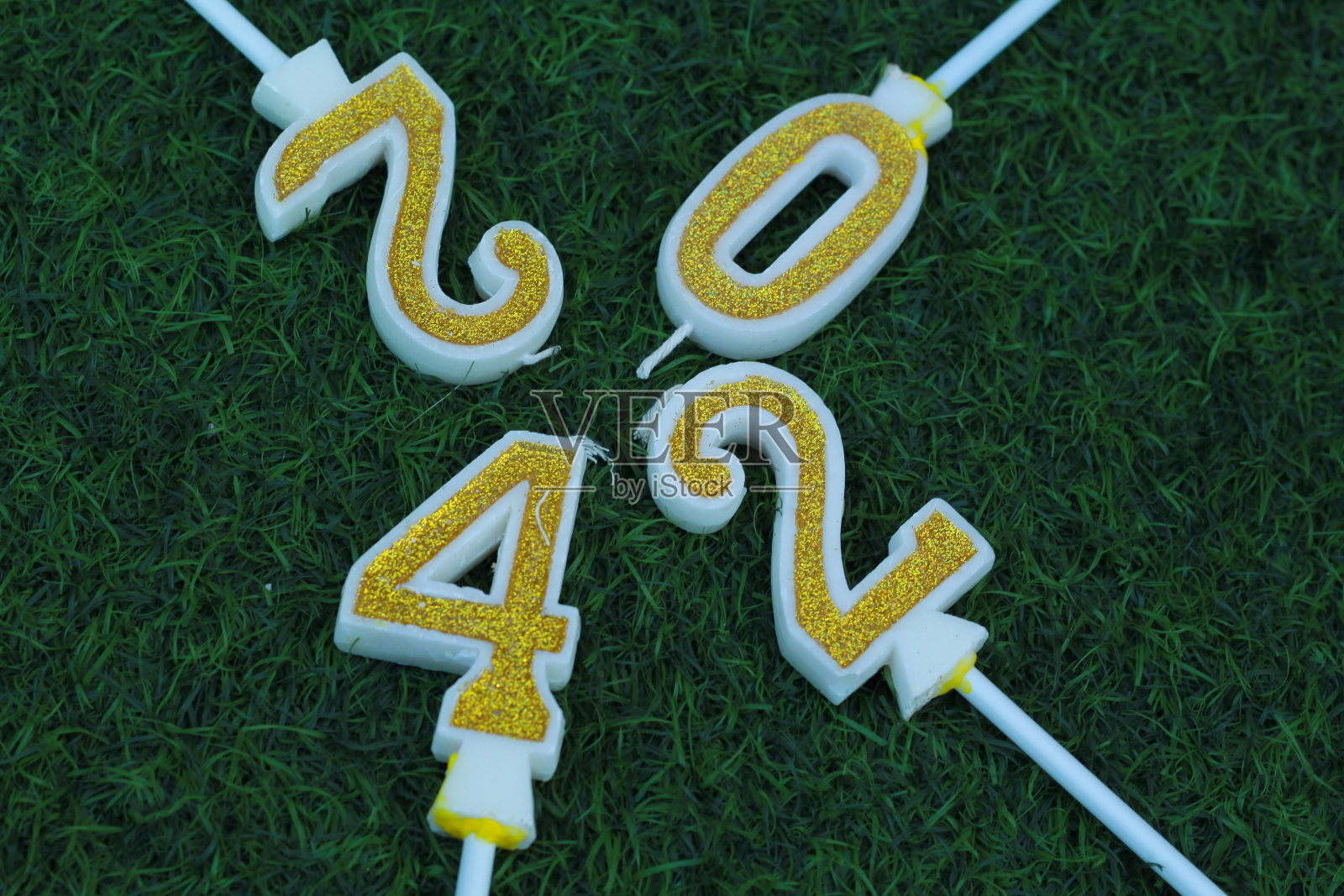 新年前夜的背景概念，在绿色的草地上，闪闪发光的金色蜡烛编号2024照片摄影图片