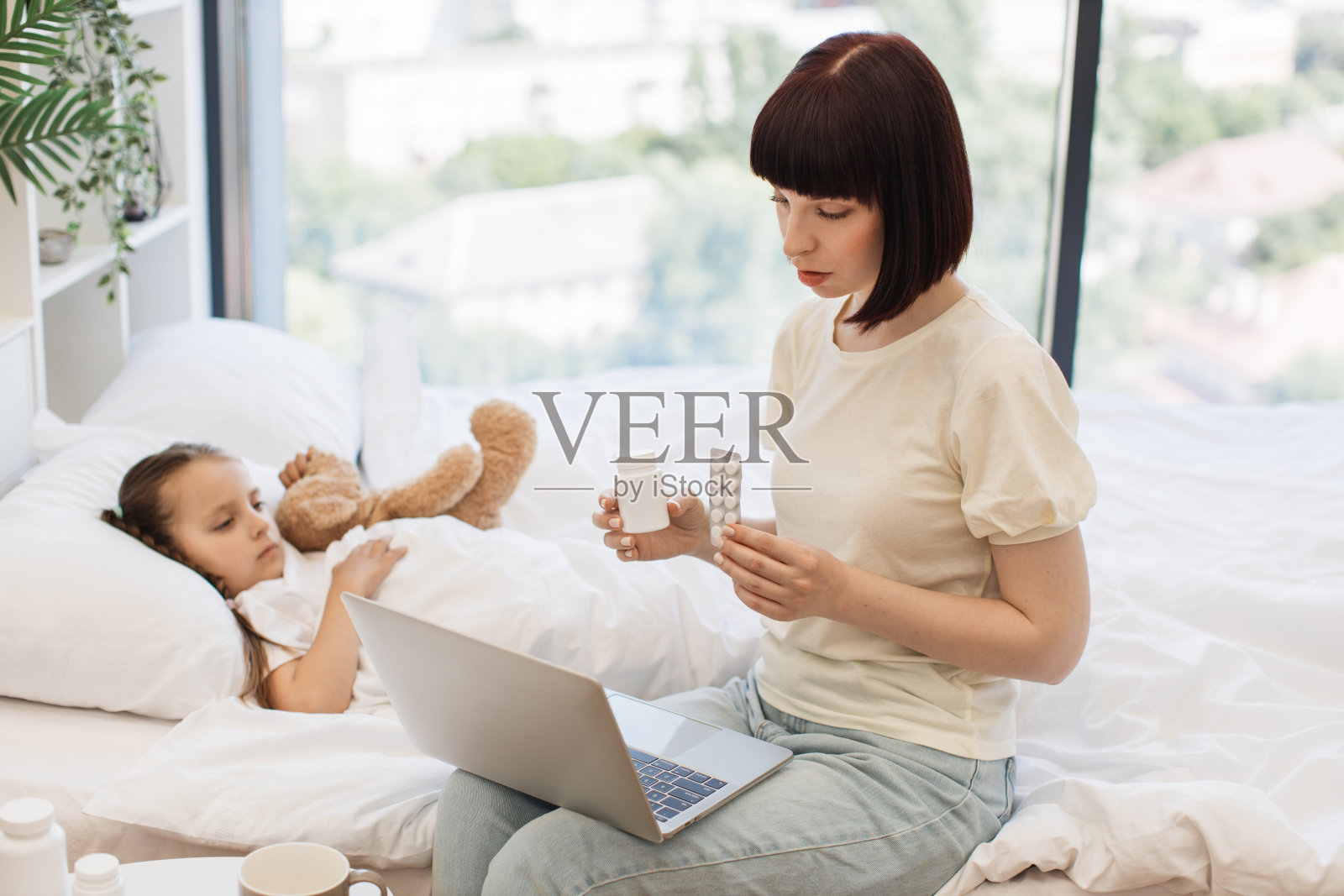 母亲用笔记本电脑为生病的孩子与医生视频聊天照片摄影图片