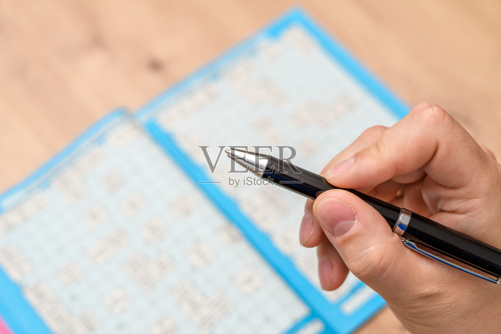 手里拿着笔，玩填字游戏照片摄影图片