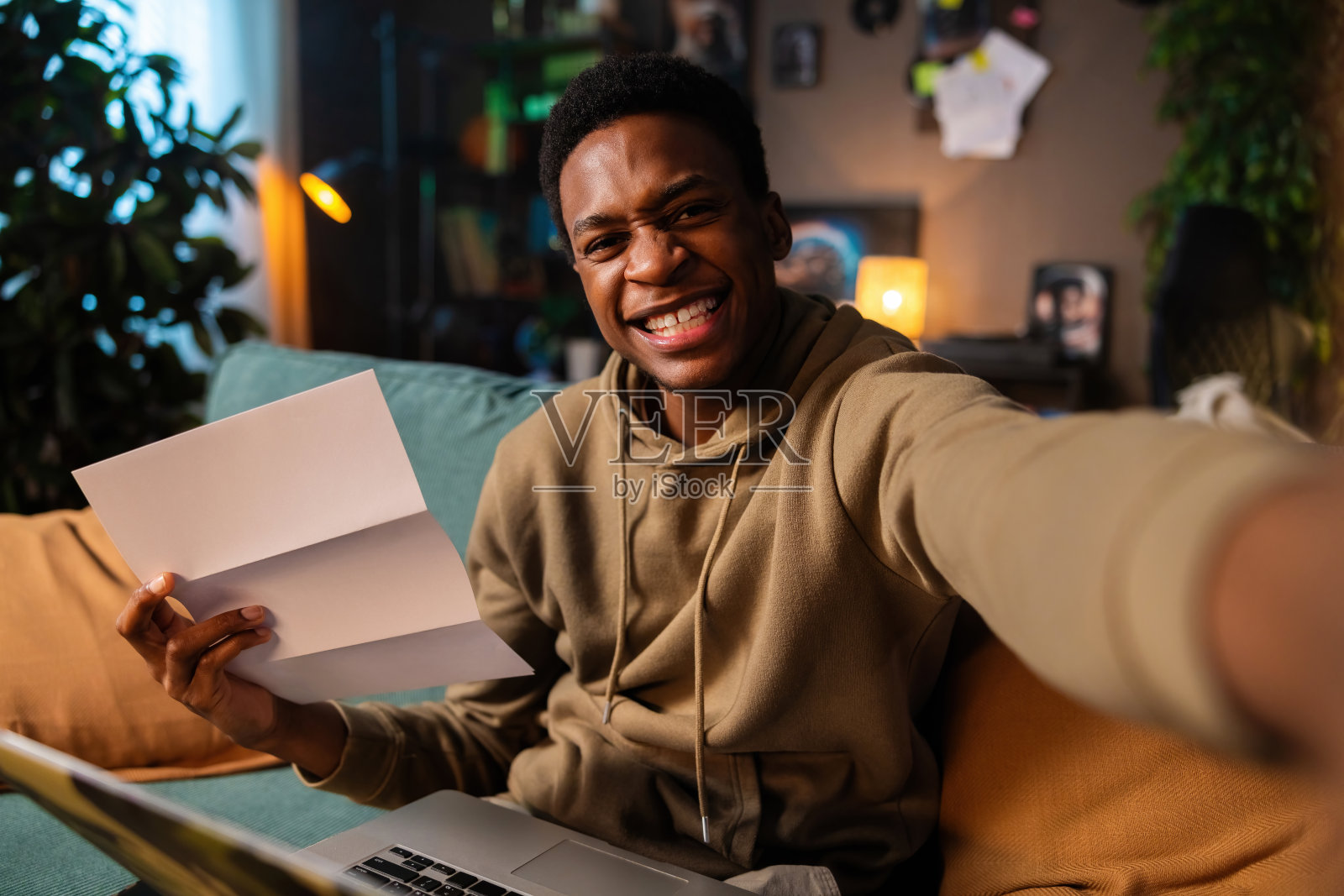 非裔美国人皮肤黝黑，自信沉着，非裔美国人穿着随意，穿着简单的衣服，坐在舒适的沙发上，手里拿着一摞文件，从法律文件到个人笔记照片摄影图片